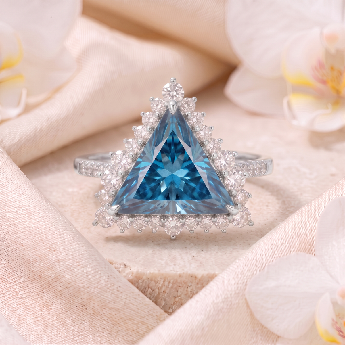 Front view of a trillion cut blue moissanite halo ring in white gold on an elegant draped background.