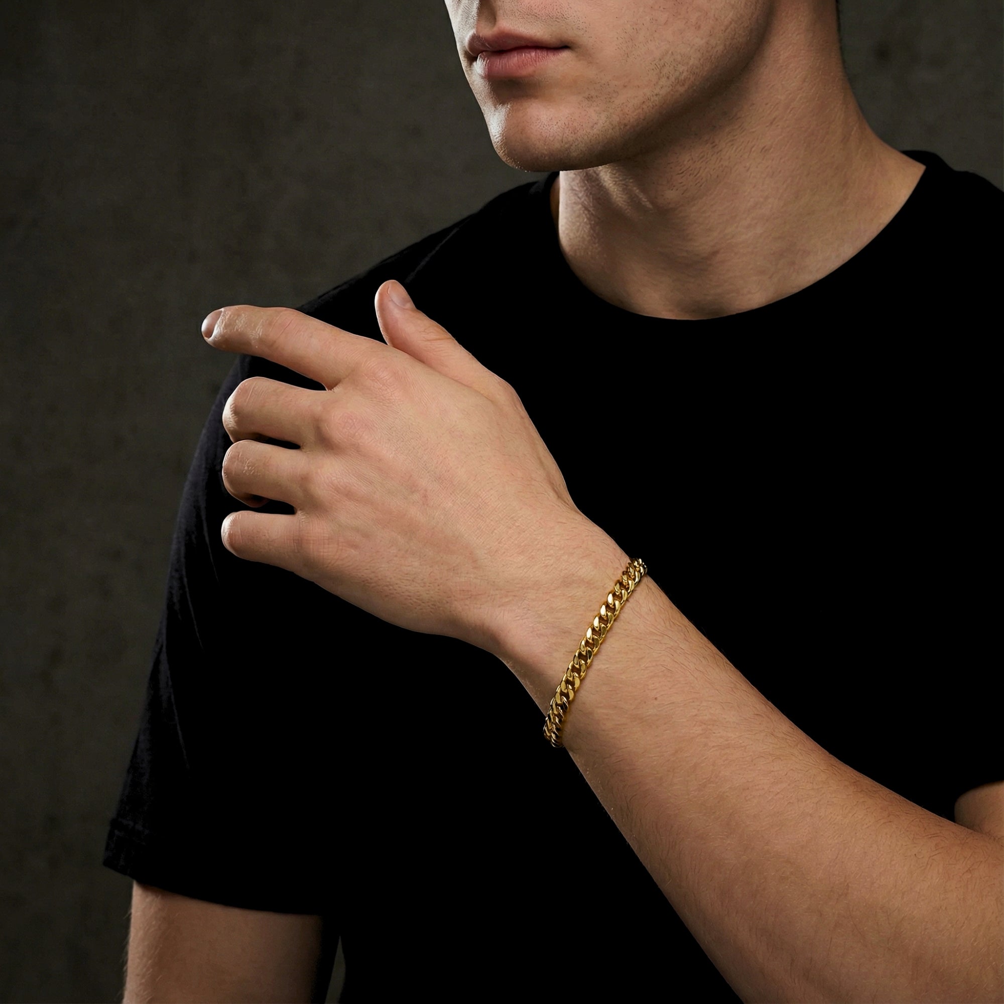 8mm gold stainless steel Cuban link bracelet worn on a man's wrist, styled with a black t-shirt.