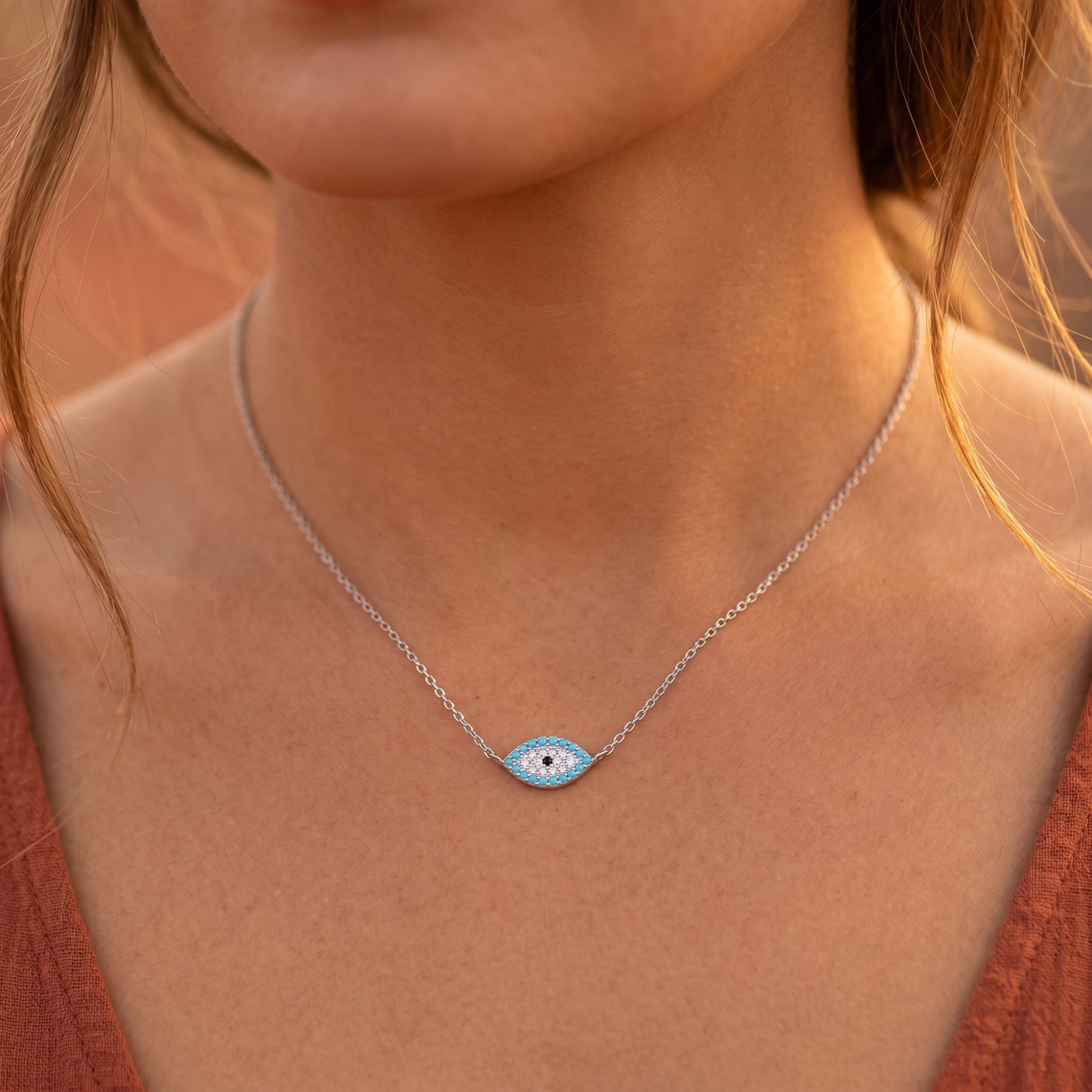 Frontal view of the silver Aegean Turquoise eye necklace worn on a model's neck, showcasing the dainty pendant.