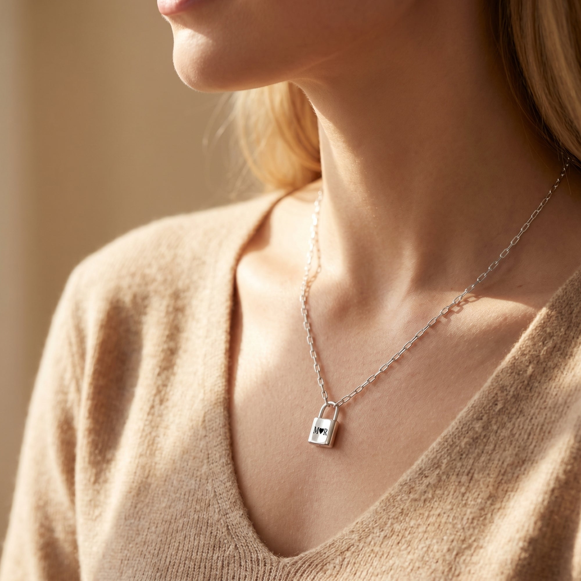 Silver stainless steel padlock pendant necklace with personalized initials worn on a neck.