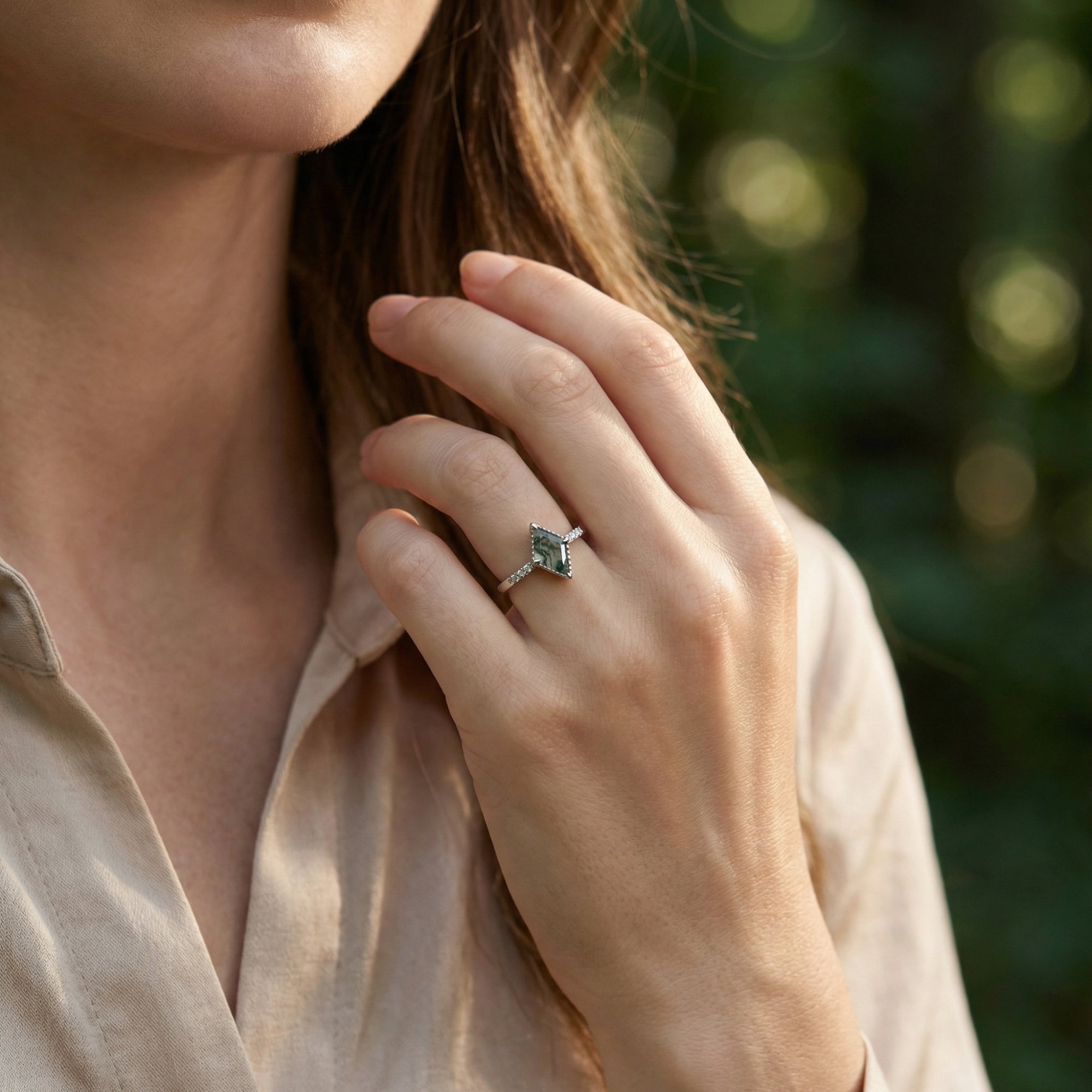 A woman wearing the kite cut moss agate sterling silver ring, showcasing its size and appearance on the hand.