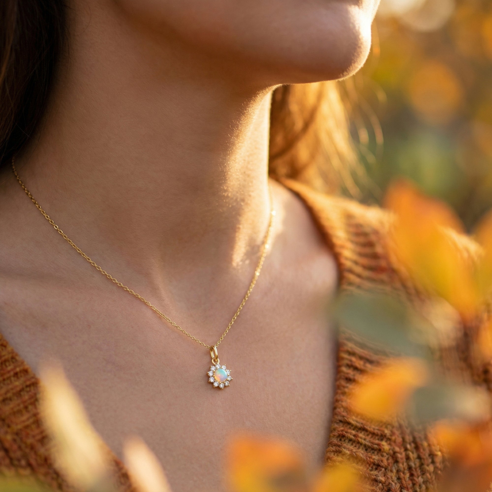 Side view of a model wearing the gold-tone Celestria round white opal necklace in warm, natural sunlight.