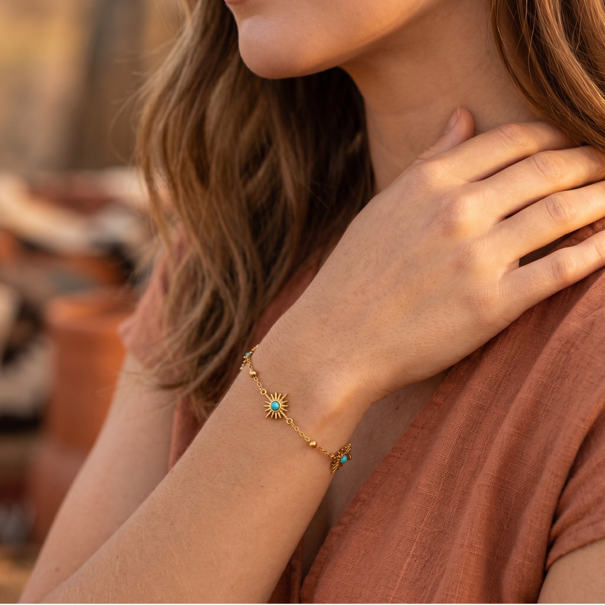 Close-up of the 18K gold finish Santa Ana bracelet with turquoise sunburst charms on a model's wrist.