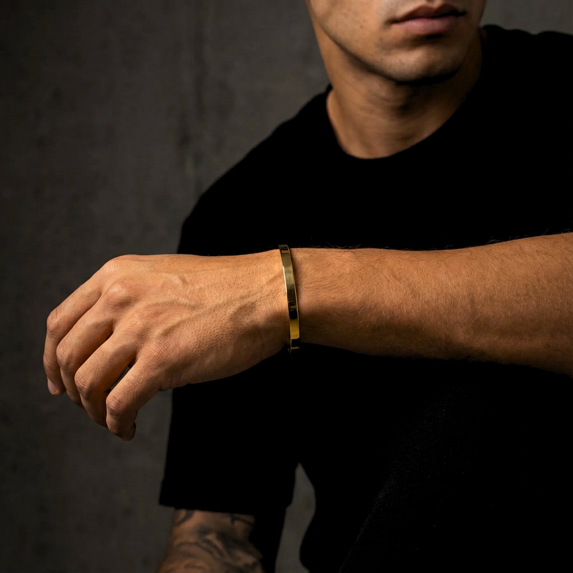 Side view of a gold stainless steel cuff bracelet worn on a man's wrist.