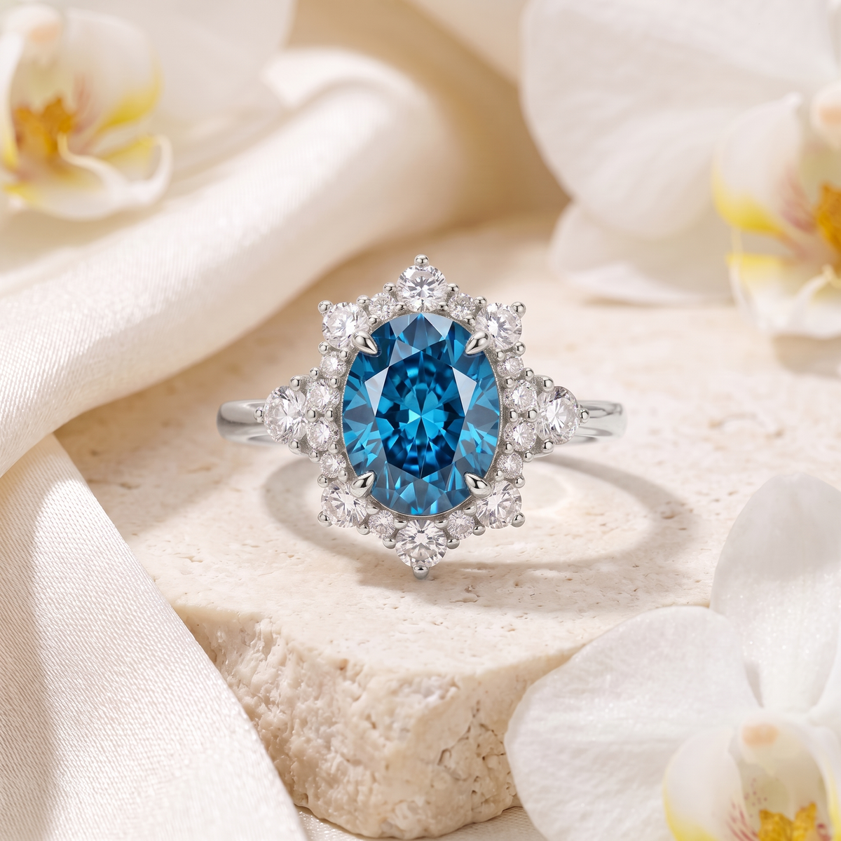Oval blue moissanite halo ring crafted in white gold, resting on a textured stone pedestal.