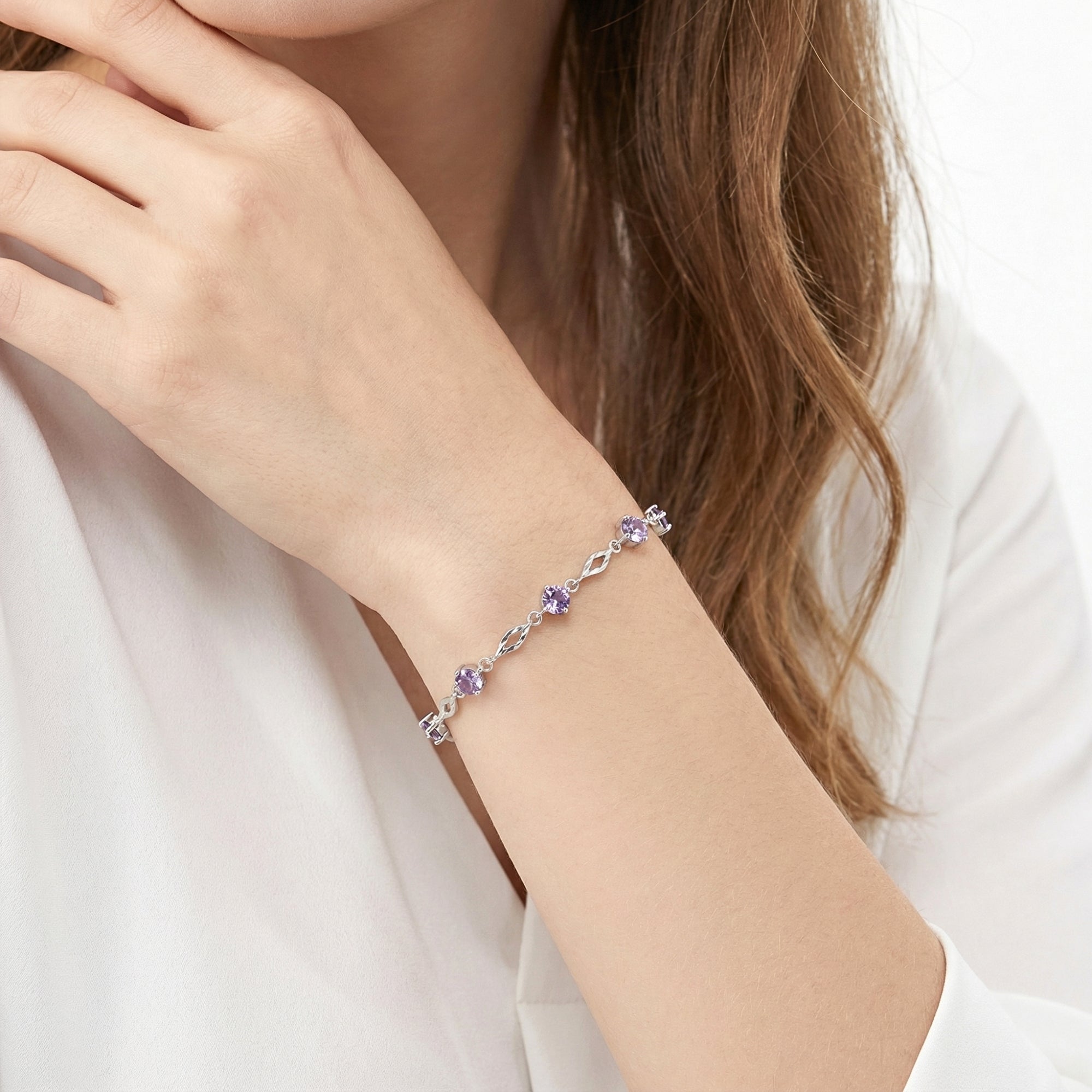 Side view of the sterling silver station bracelet with violet simulated amethysts worn on a model's wrist.