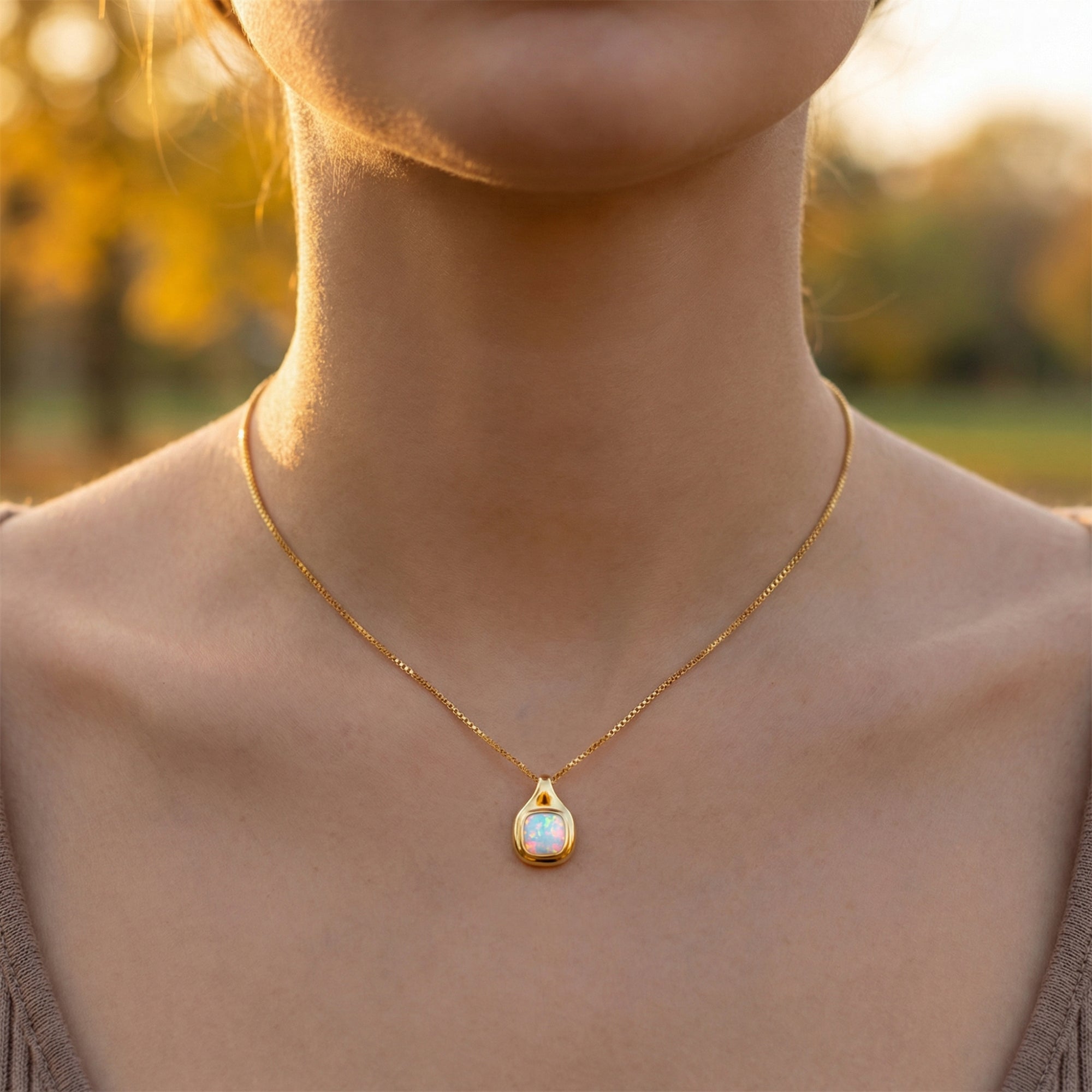Frontal view of the gold vermeil cushion cut white opal necklace on a model's neckline.