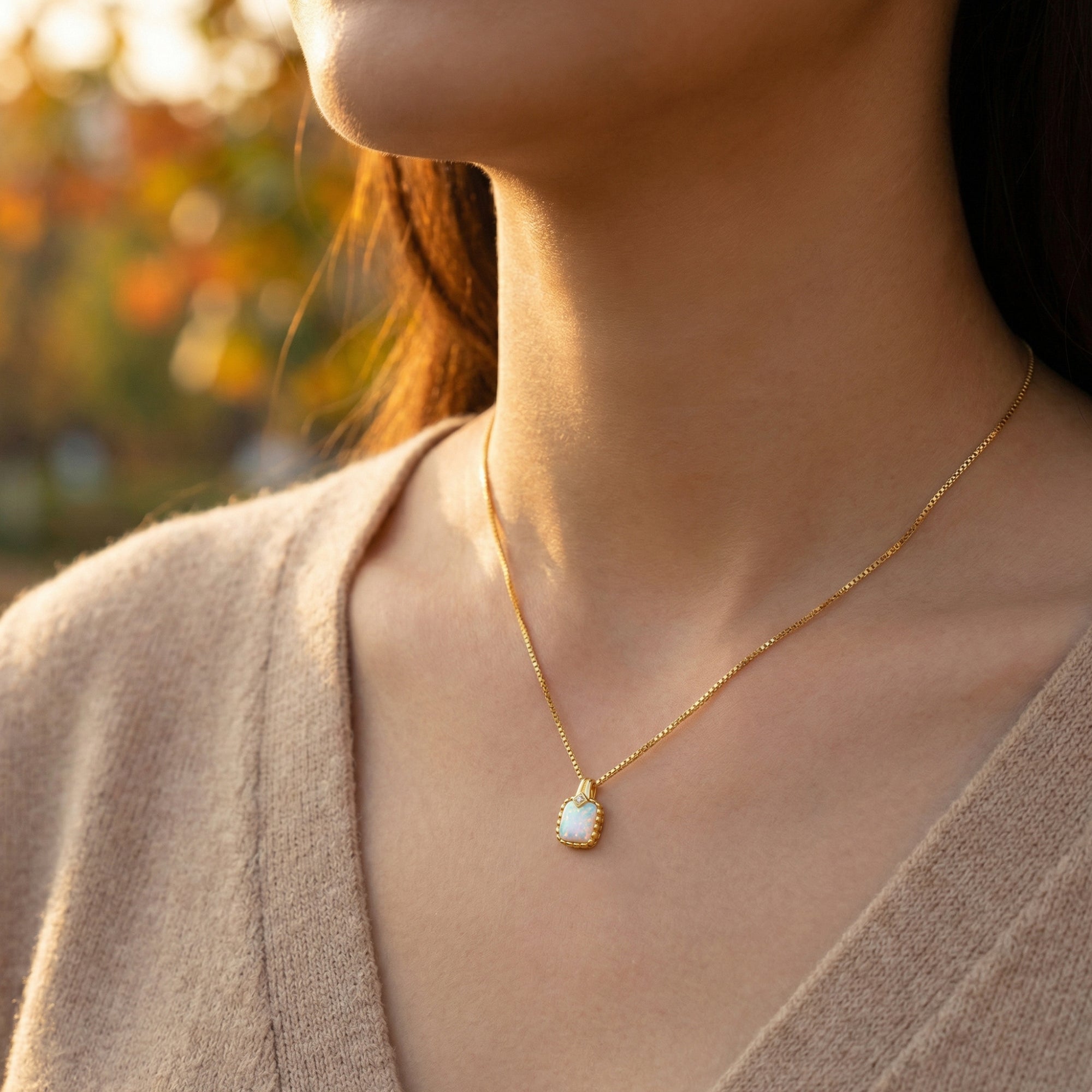 Side view of a model wearing the dainty gold cushion cut white opal pendant necklace.