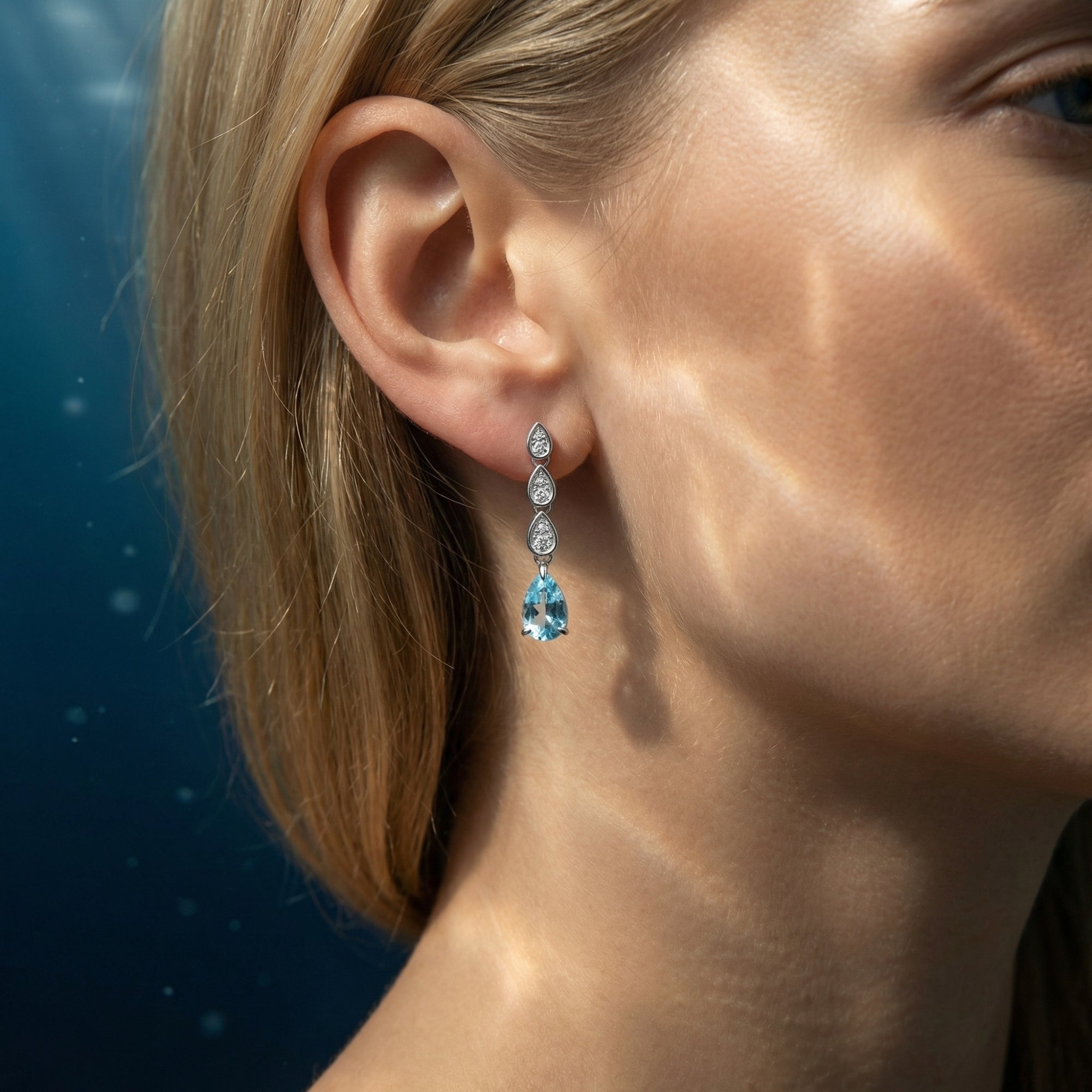 Side profile of a model wearing the Neriella platinum pear cut aquamarine drop earrings.