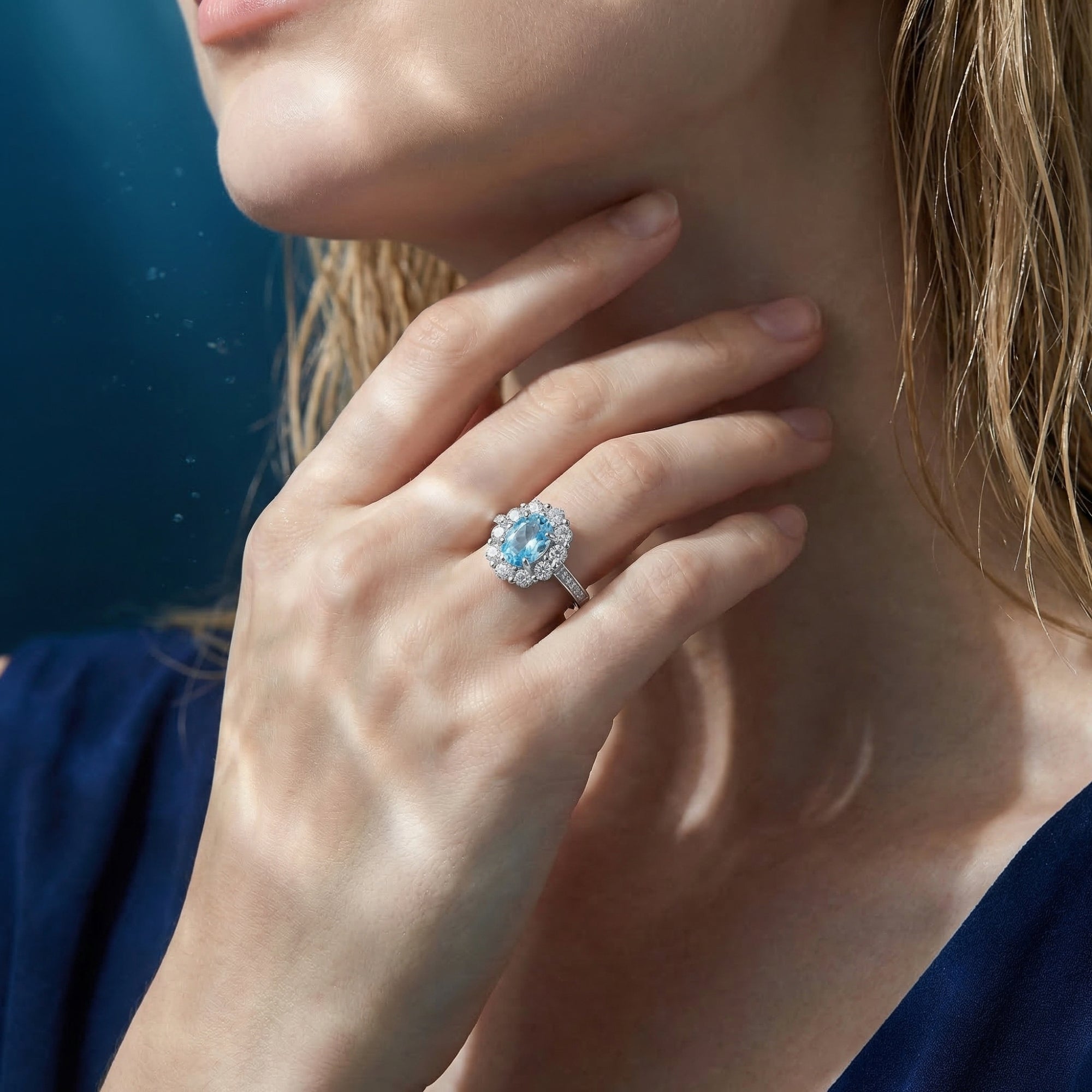 Model wearing the Delphinia aquamarine ring in silver, showcasing the oval cut stone against a blue dress.