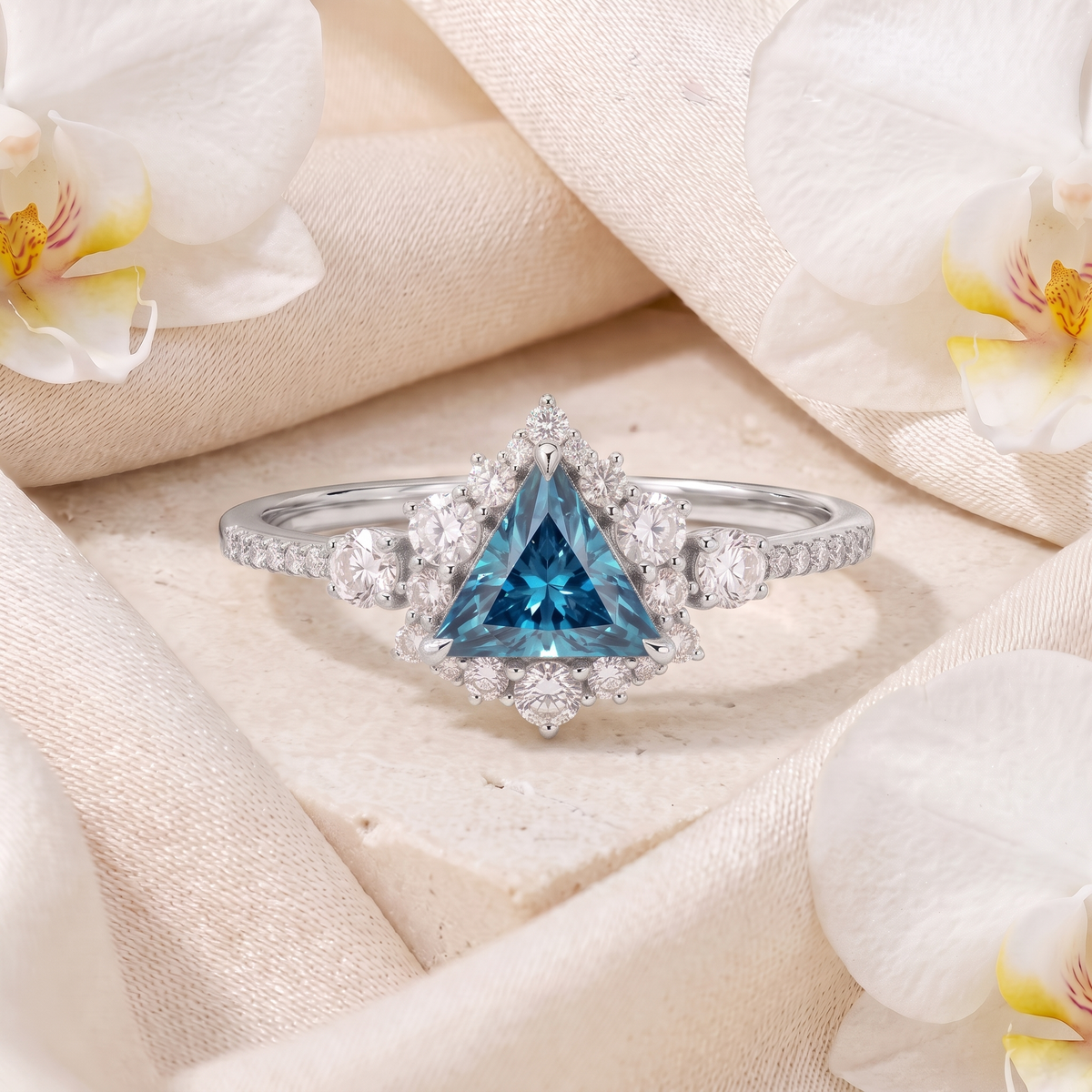 White gold triangle cut blue gemstone ring with diamond halo and pavé band.