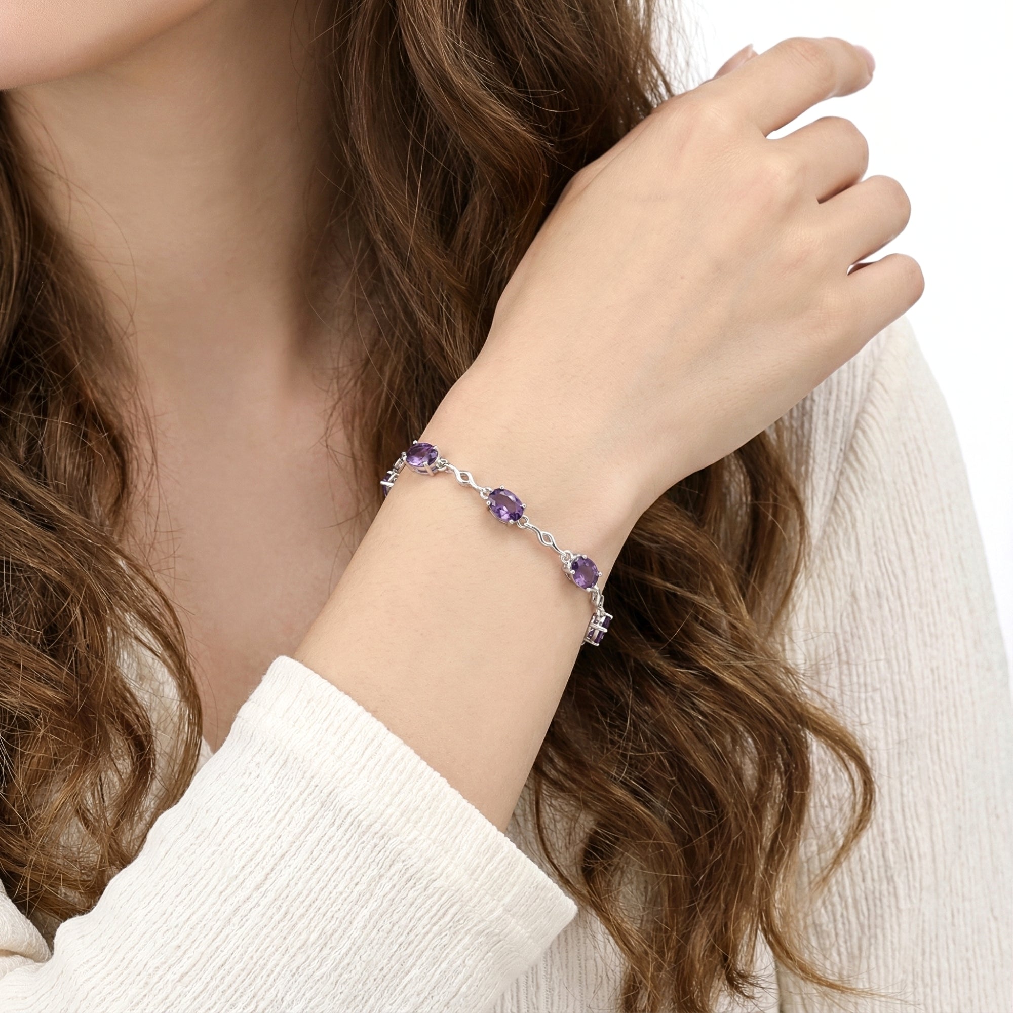 Close-up of the sterling silver Estella station bracelet with simulated amethyst stones on a woman's wrist.