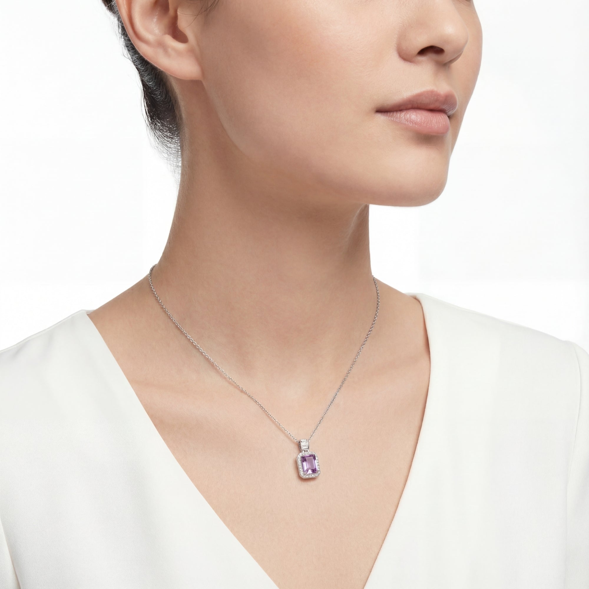 Woman wearing the Rosalie sterling silver necklace with an emerald cut purple simulated amethyst pendant.