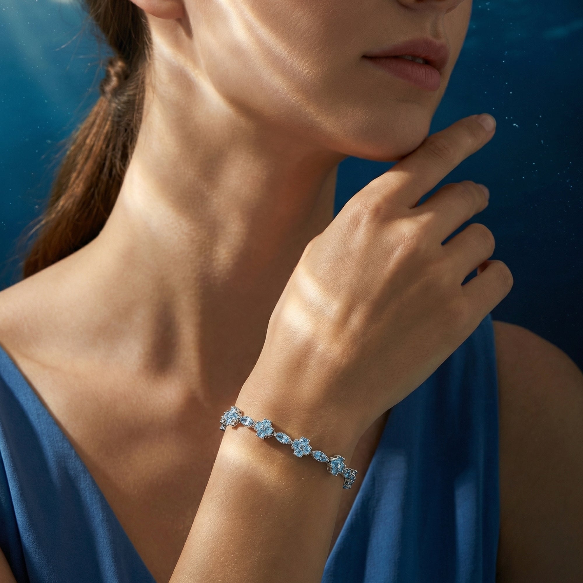 Model wearing a silver aquamarine station bracelet on her wrist, styled with a blue dress.