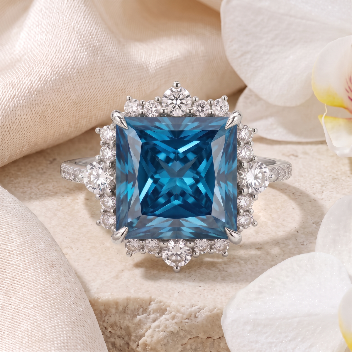 Front view of a white gold princess-cut blue moissanite halo engagement ring on stone.