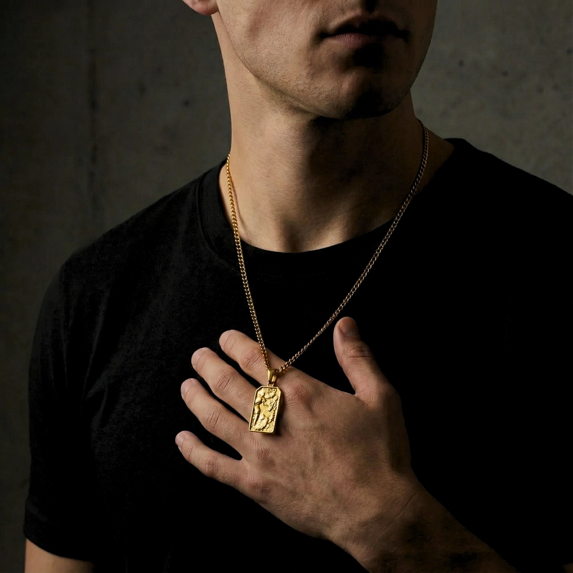 Model holding the gold St. Michael Archangel pendant to provide a scale reference and show the intricate engraving.