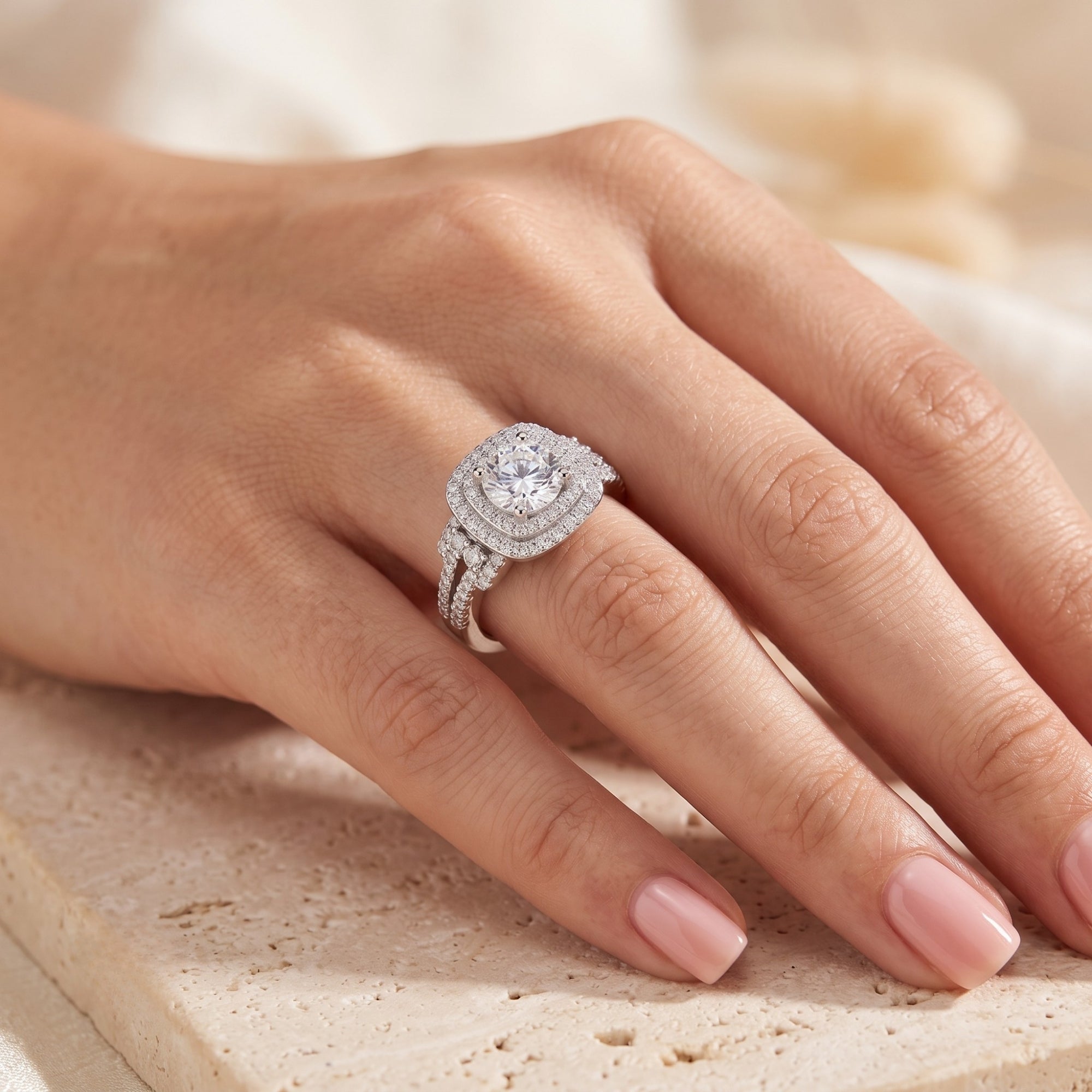 Sterling silver cushion double halo ring with cubic zirconia shown on a finger.