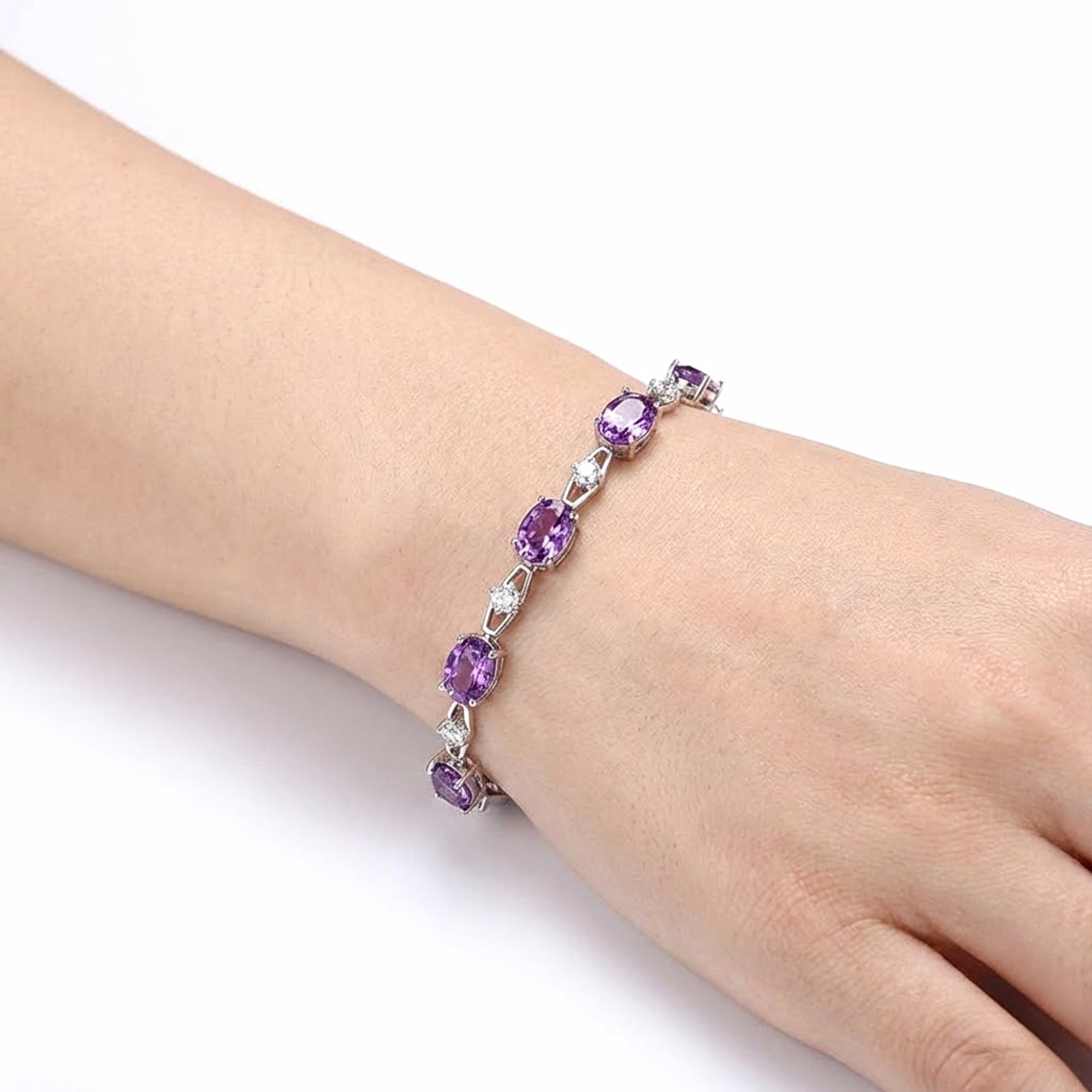 Top view of the S925 sterling silver link bracelet with oval simulated amethysts worn on a woman's wrist.