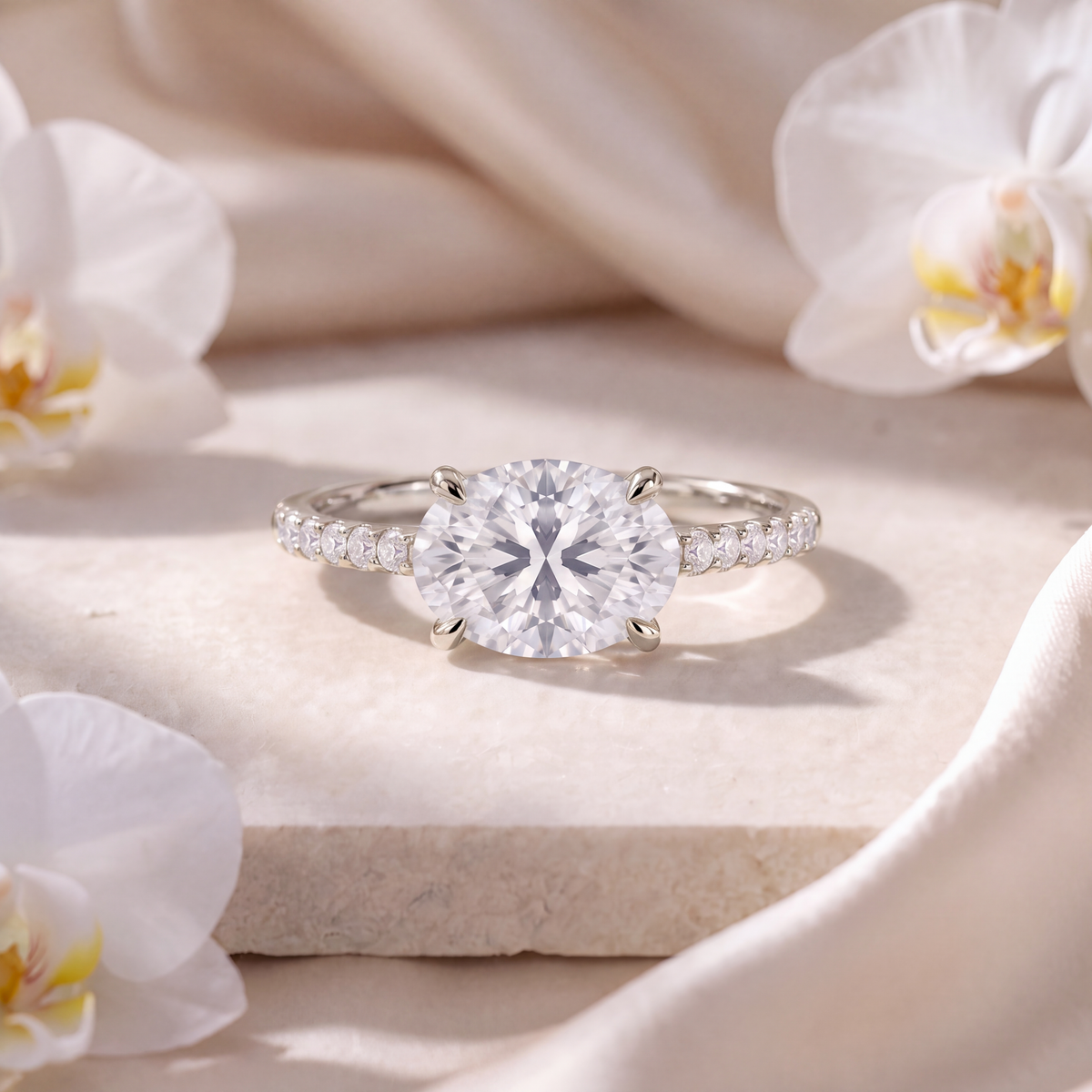 White gold east-west oval moissanite engagement ring with a pave diamond band on display.