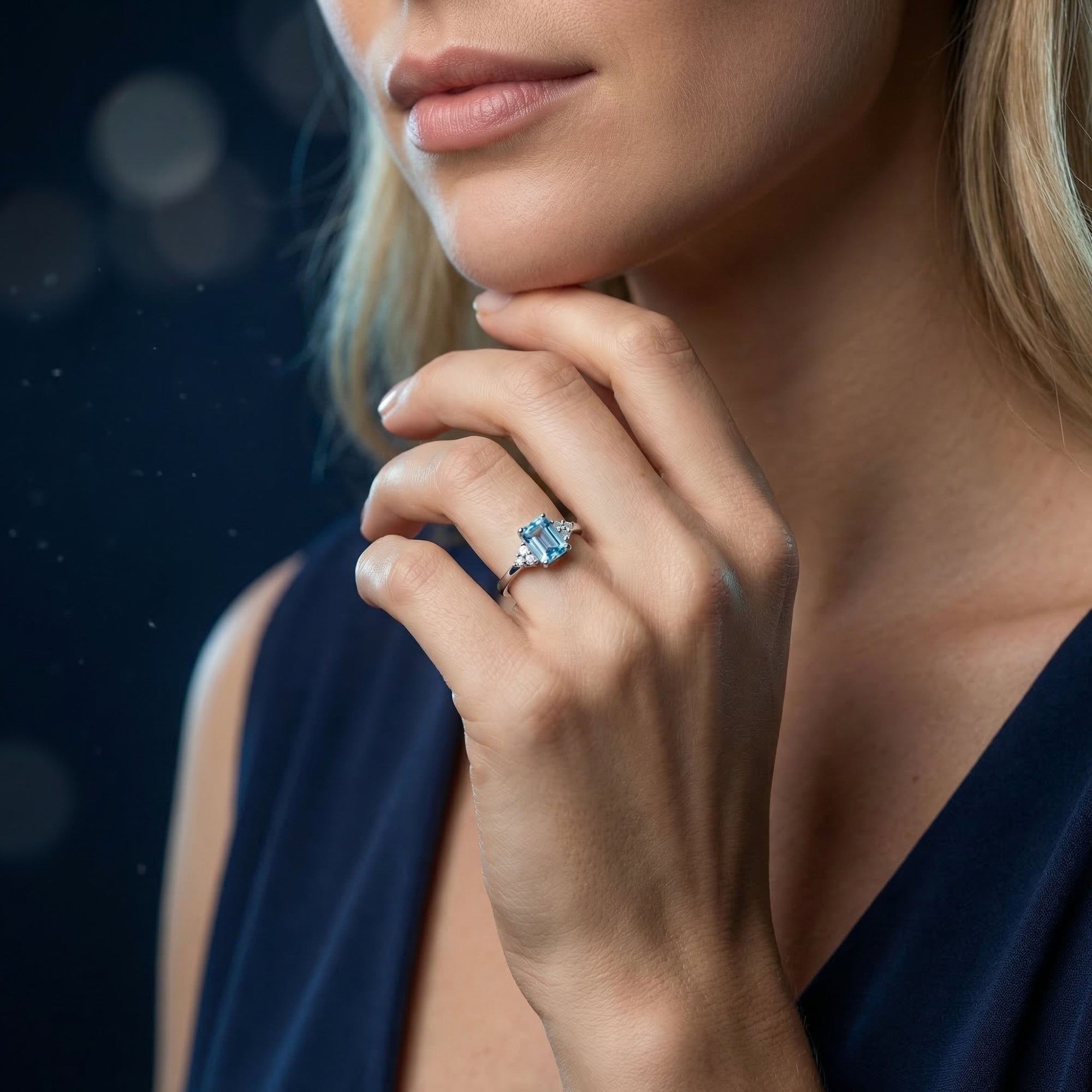 Emerald cut natural blue topaz sterling silver ring shown on a woman's hand for scale and style.