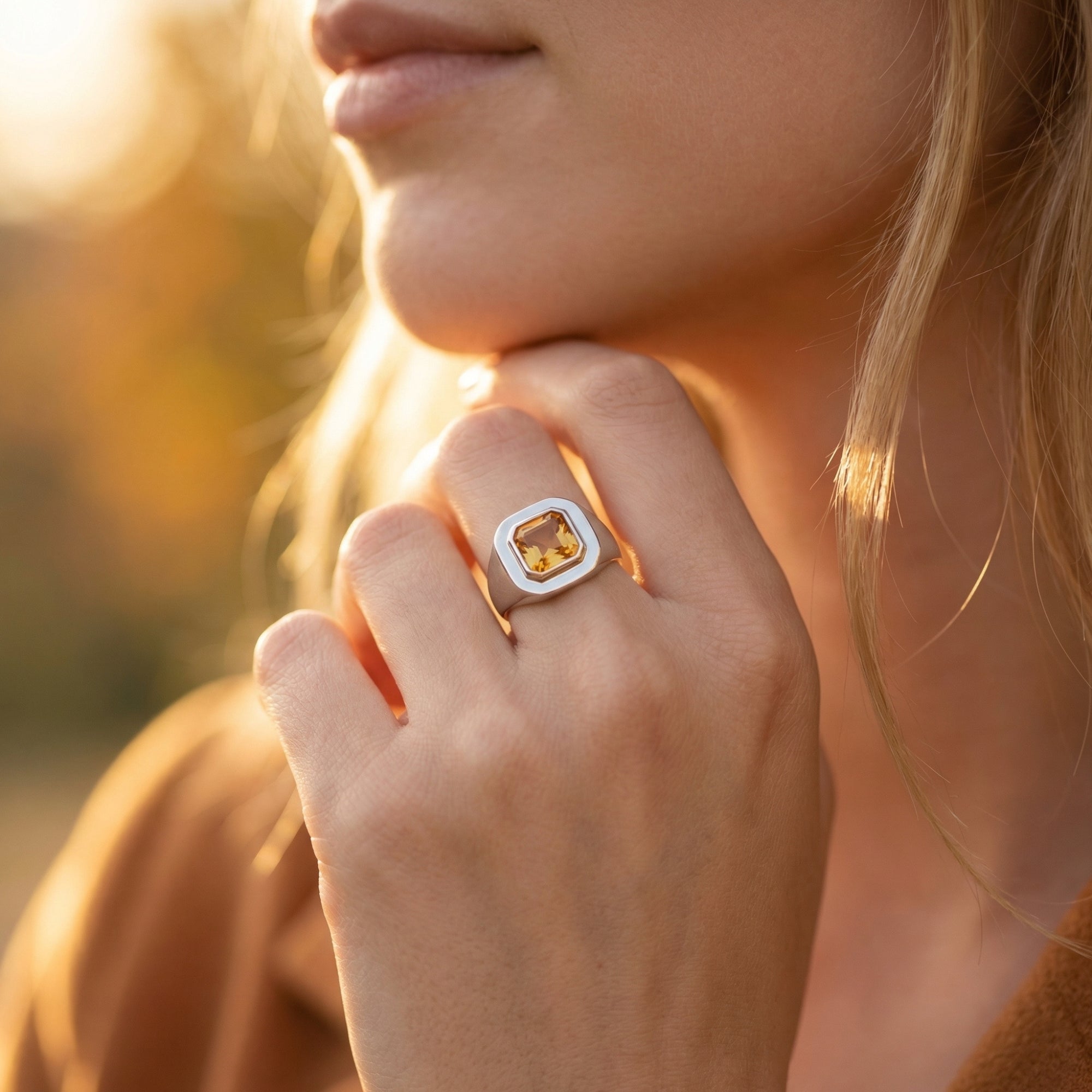 Close-up of the silver natural citrine Asscher-cut ring worn on a model's hand during golden hour.
