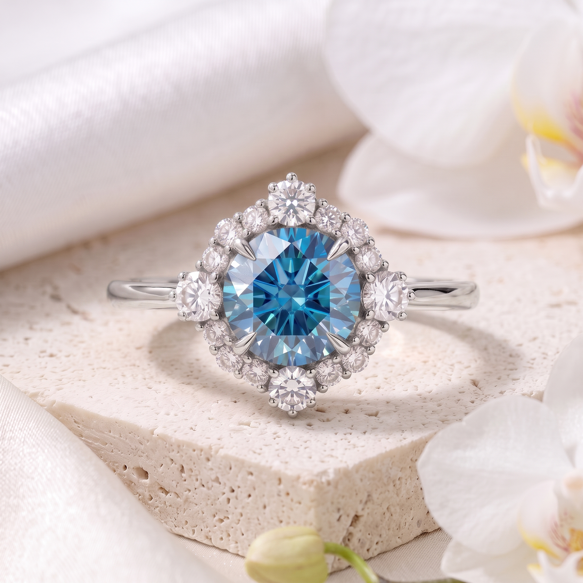 White gold halo ring featuring a round brilliant-cut blue moissanite center stone with surrounding round moissanite accents.