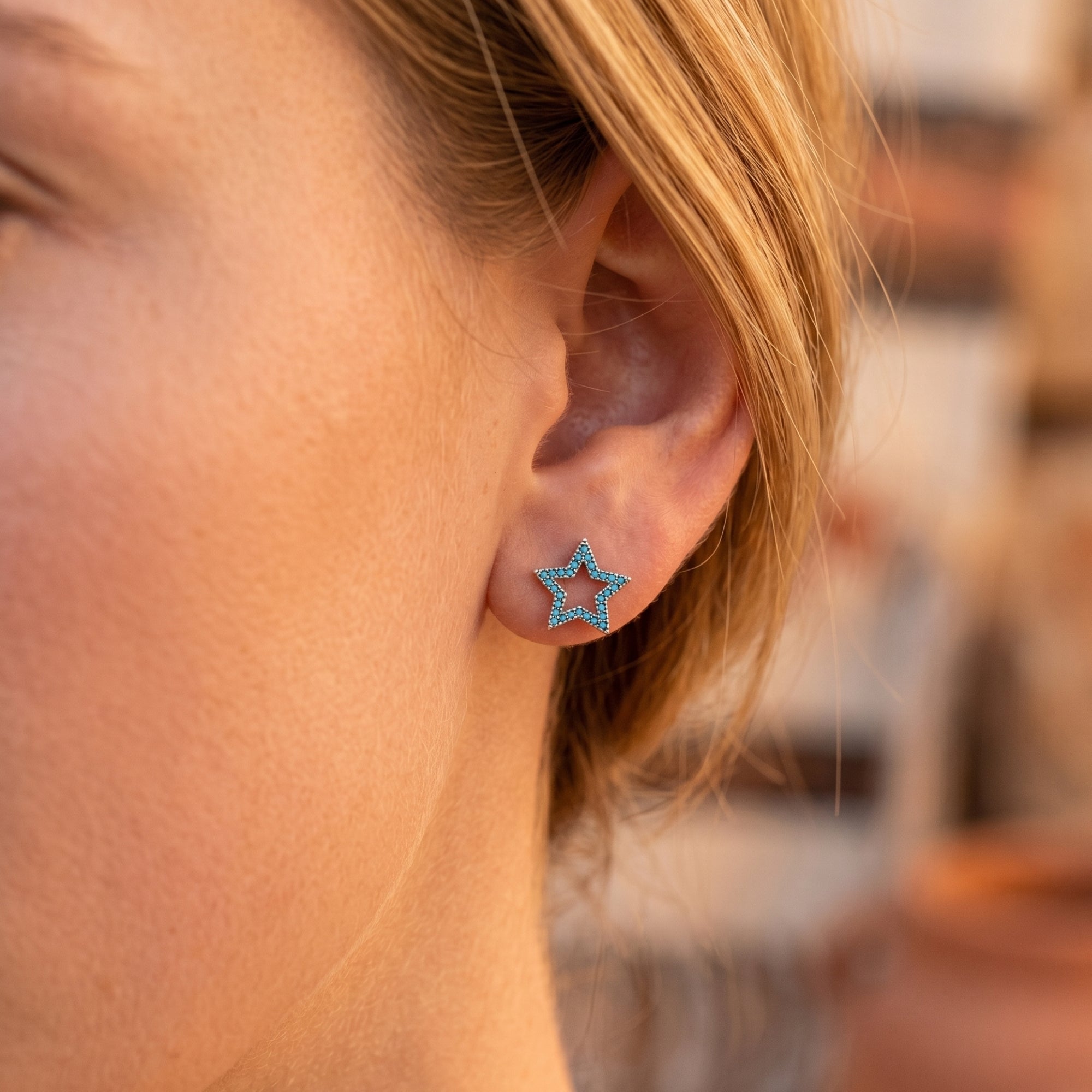 Close-up of a turquoise pave star earring in S925 sterling silver worn on a woman's ear.