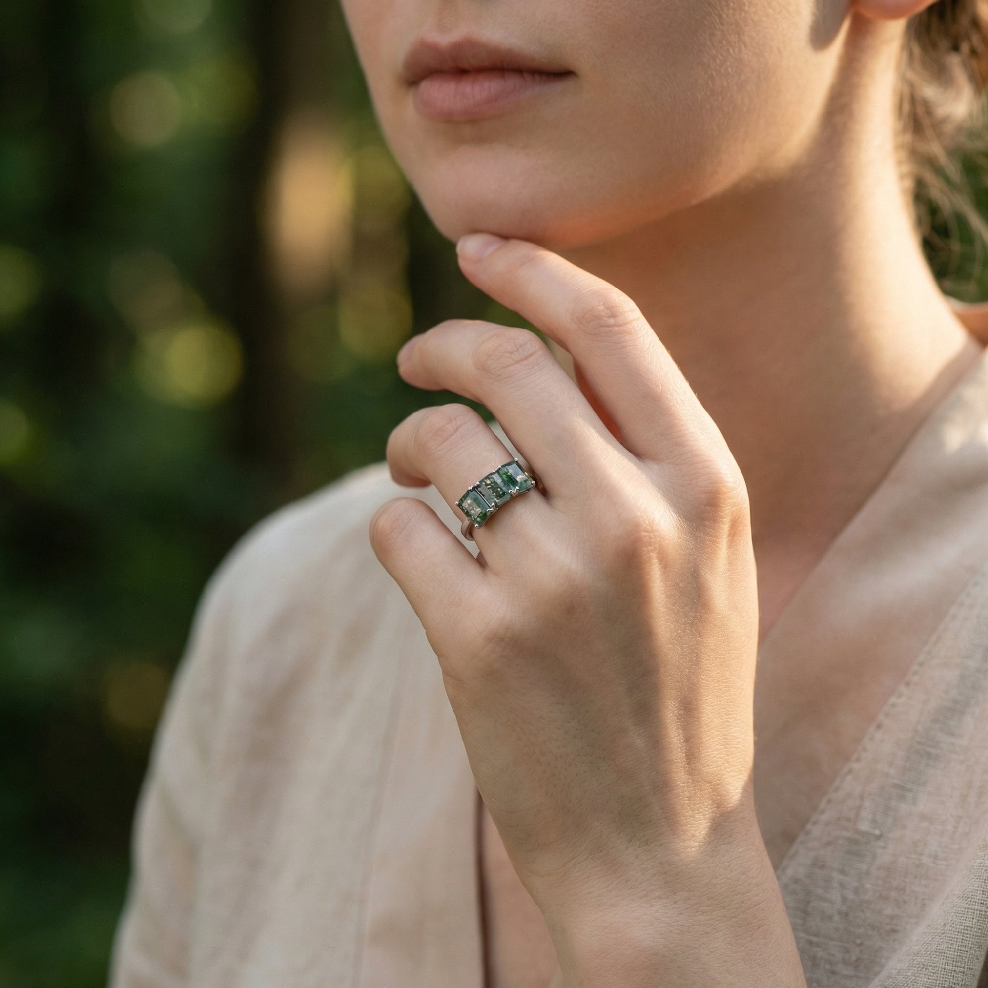 A woman's hand showcasing the green moss agate bar ring in S925 sterling silver against a natural backdrop.