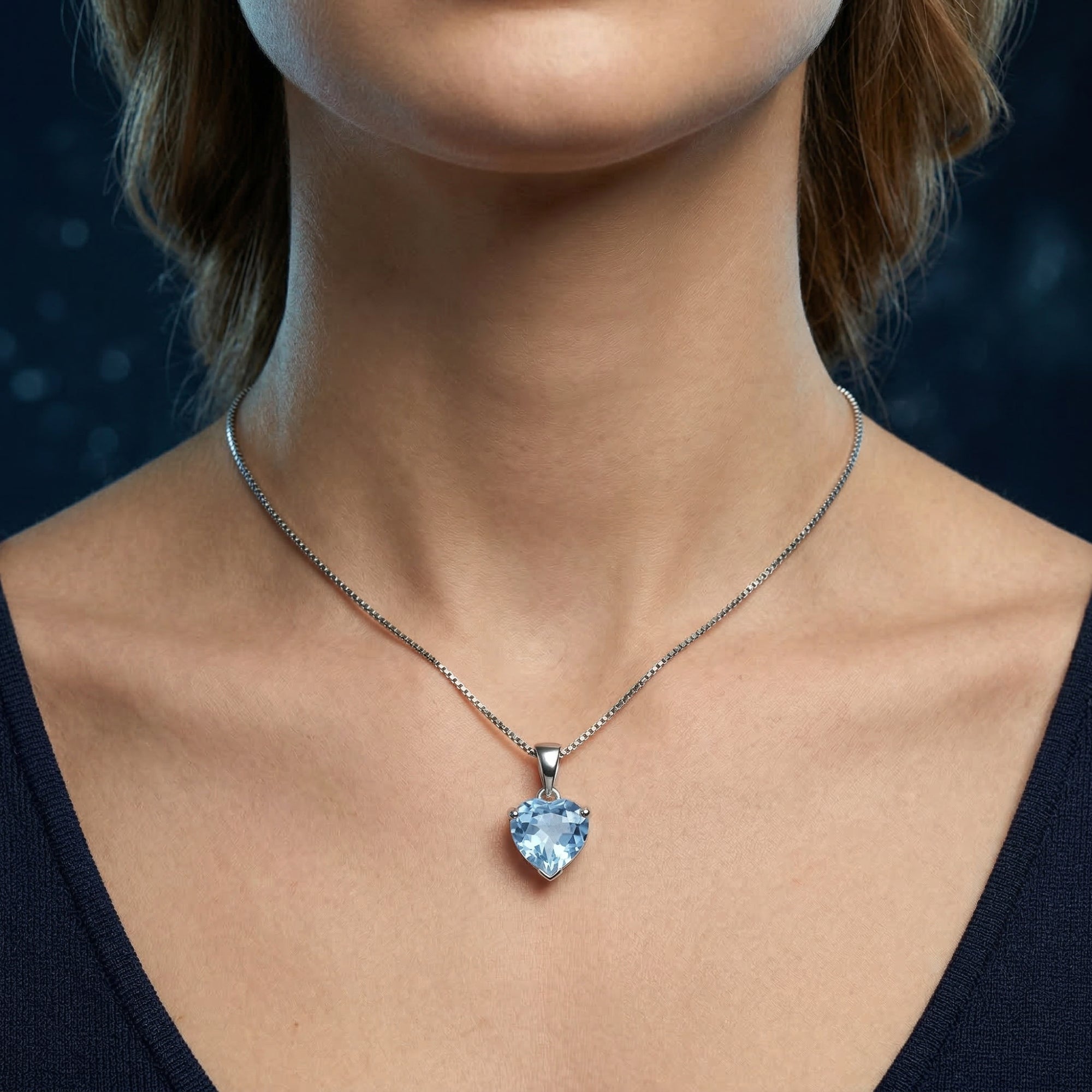 Front view of a model wearing the heart-cut natural blue topaz necklace in white gold.