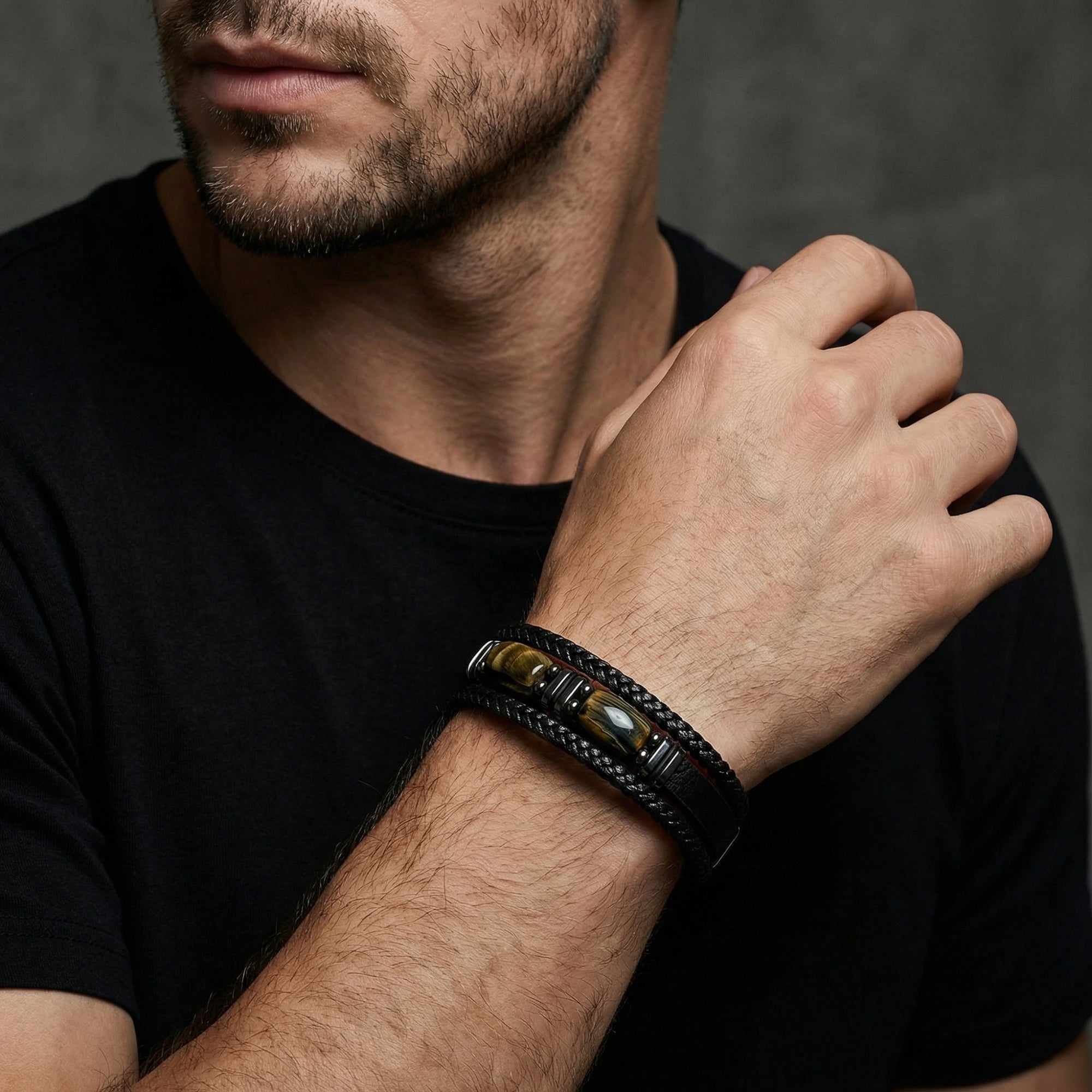 The Crucible black leather and tiger's eye bracelet with black stainless steel styled on a man's wrist.