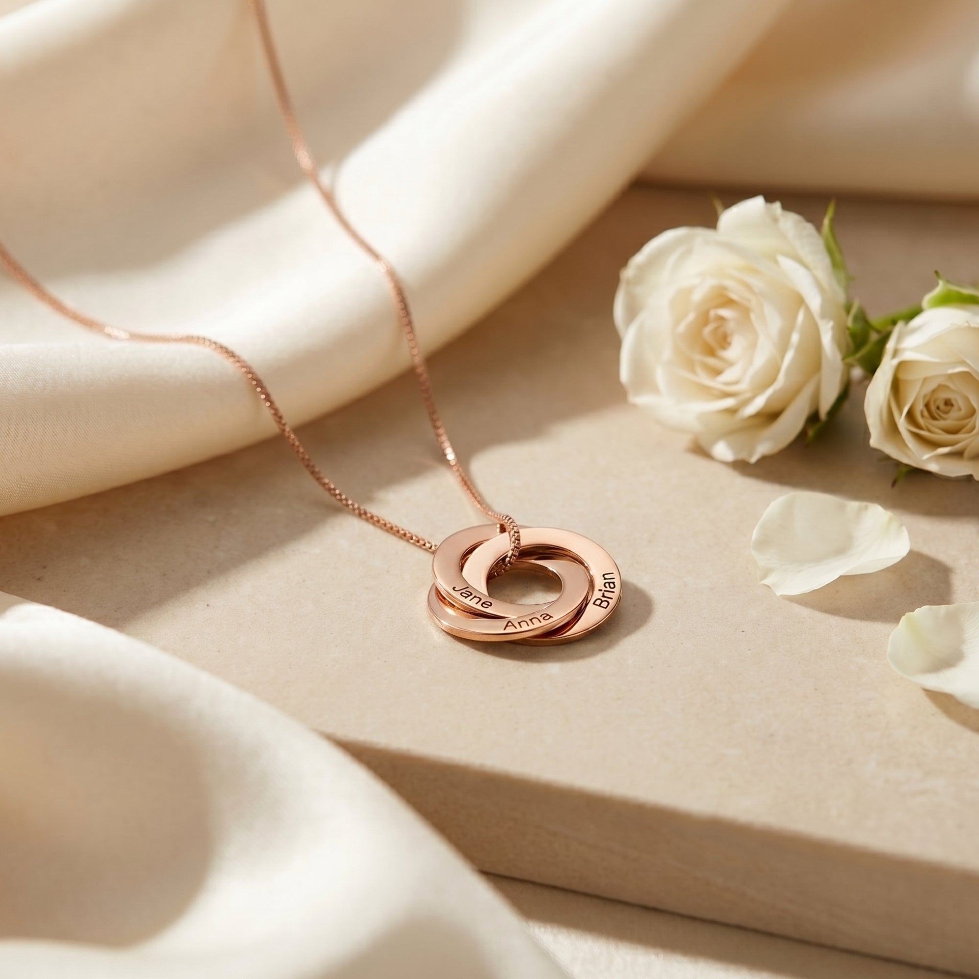 Rose gold Camilla necklace with three interlocked engraved rings with white roses.