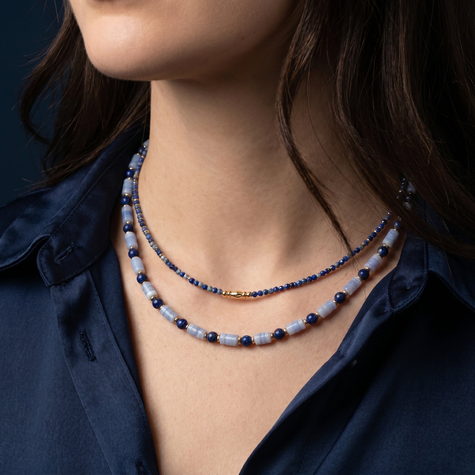 Layered view of the natural lapis and light blue bead necklace set on a model with 18k gold plated details.