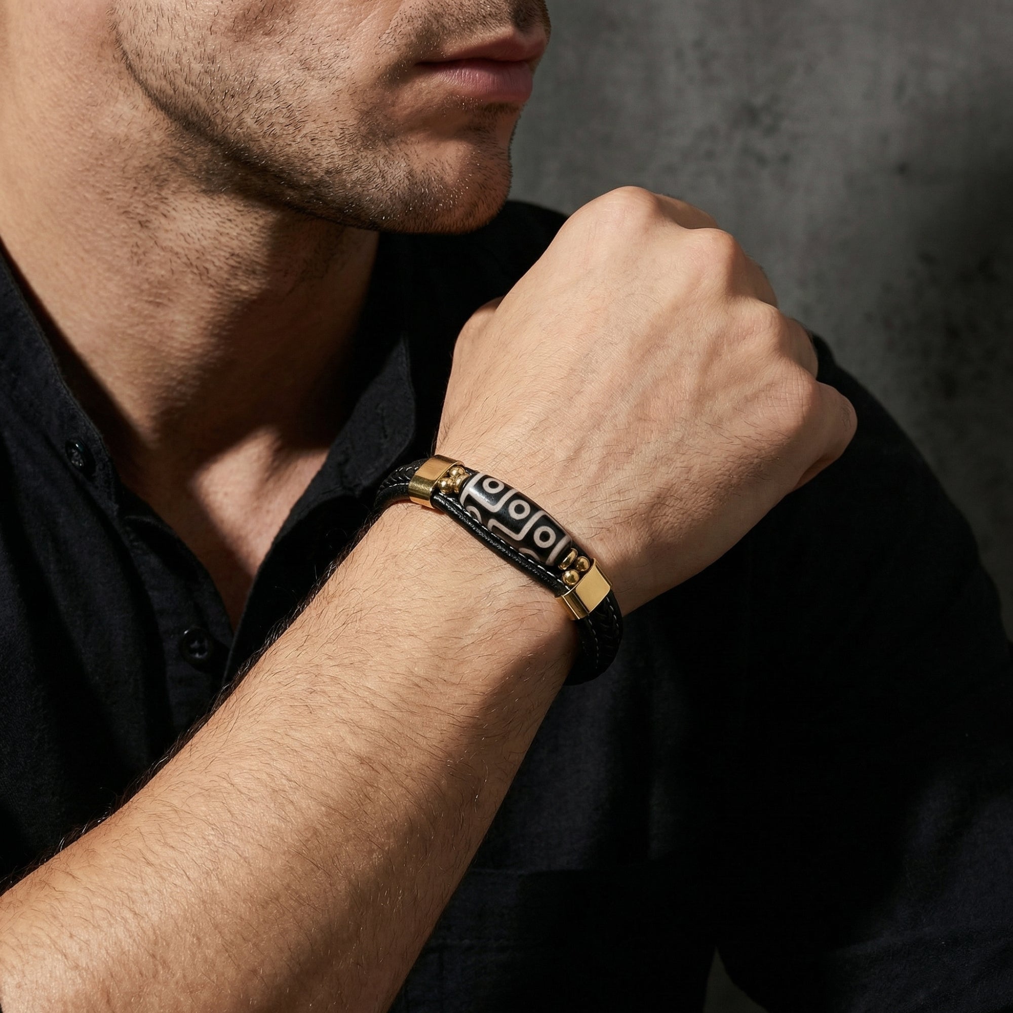 Men's Enigma leather bracelet with gold finish hardware shown on a model's wrist.