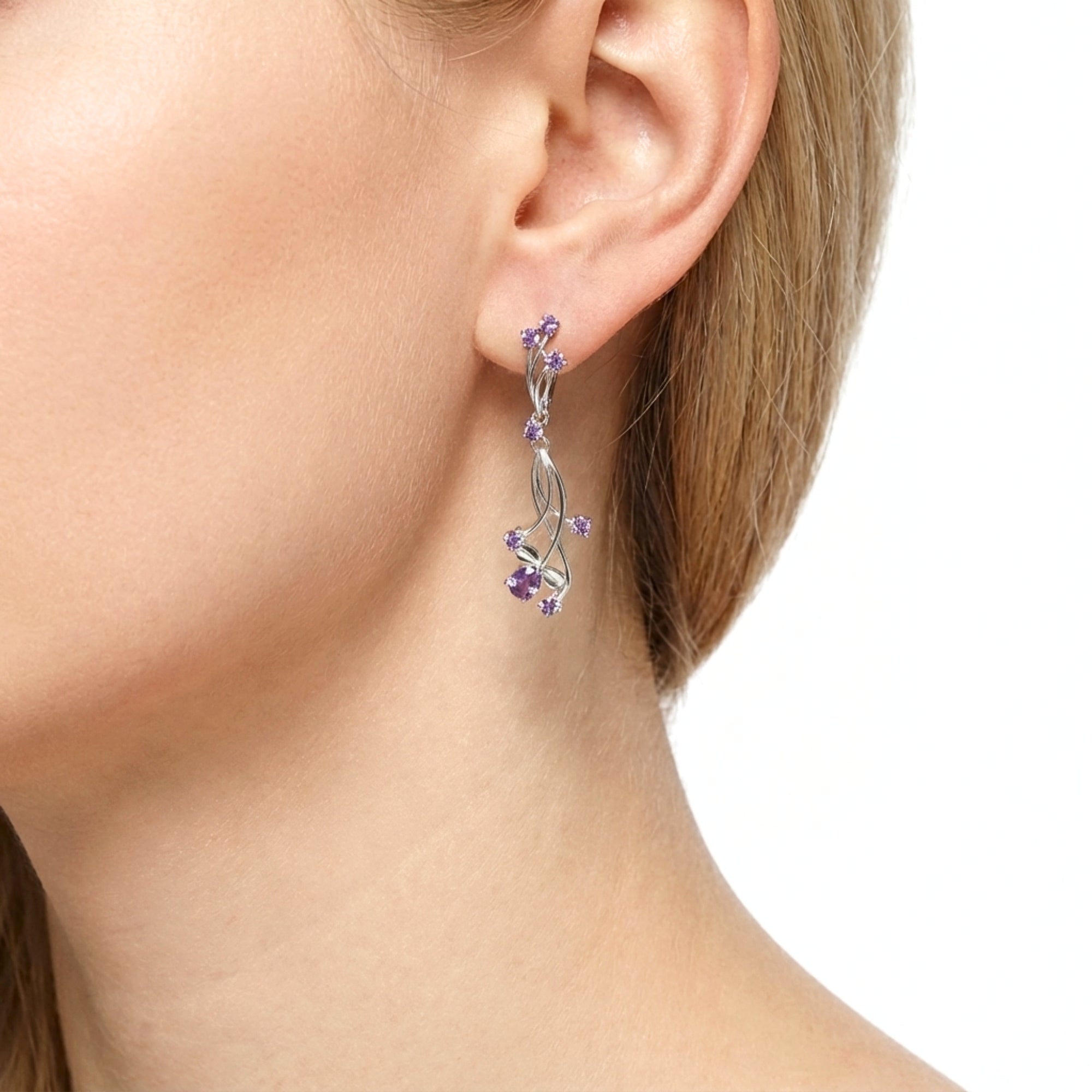 Close-up of a sterling silver Lyriel drop earring with purple simulated amethyst stones on a model's ear.
