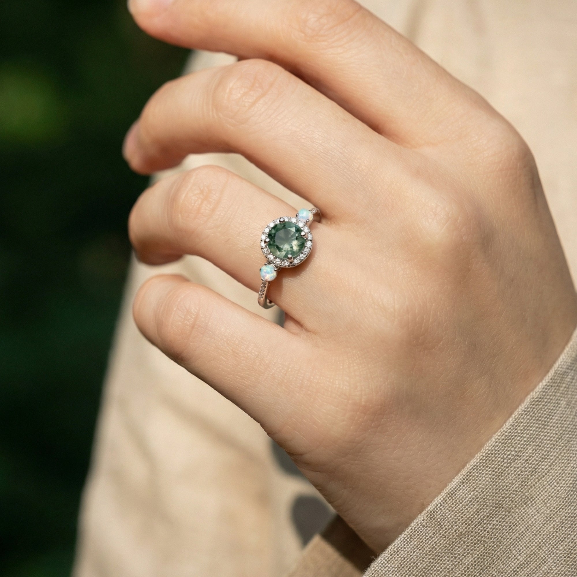 Close-up of the halo round cut moss agate and opalescent ring in S925 sterling silver on a model's hand.