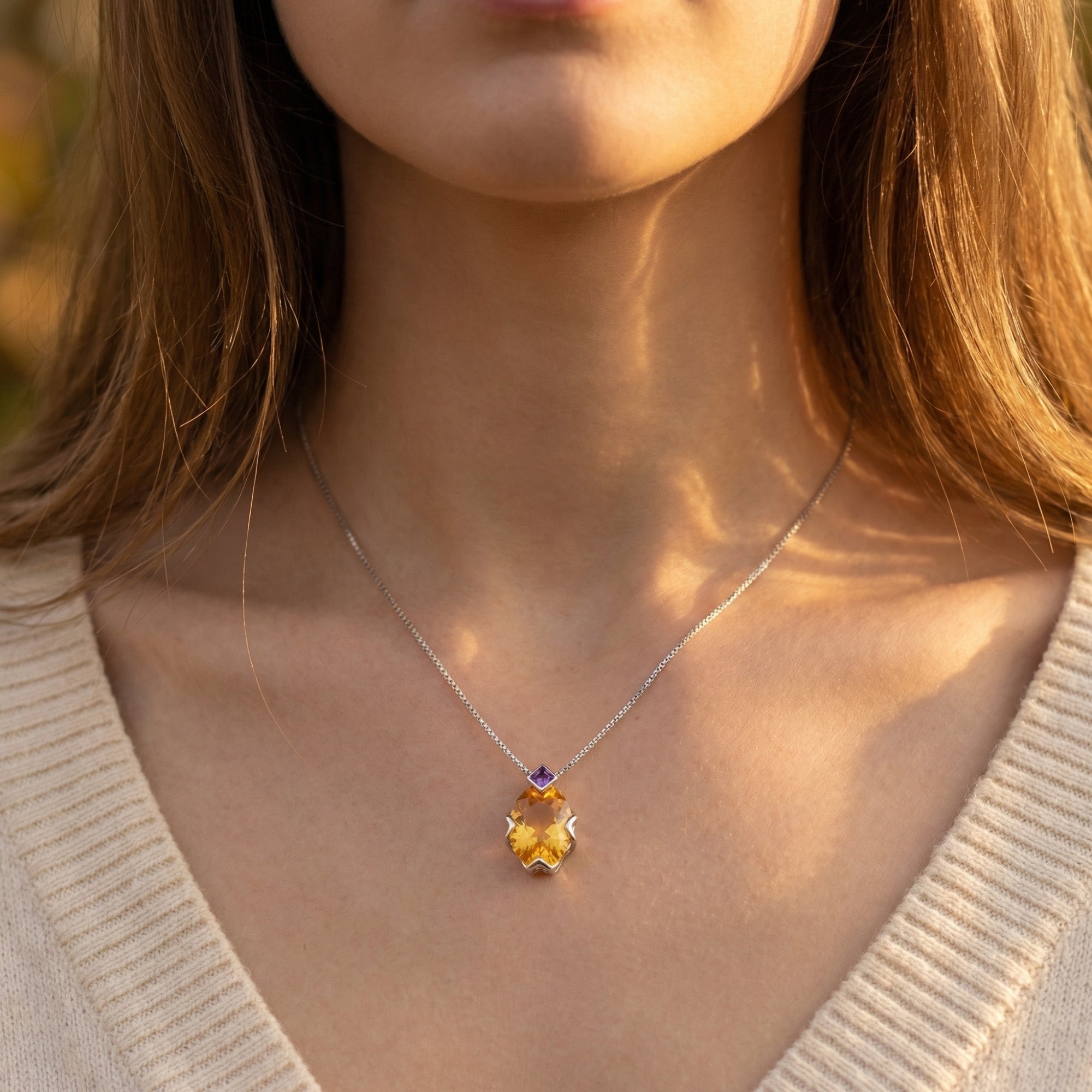 Front view of a woman wearing the oval-cut citrine and amethyst pendant on a silver chain.