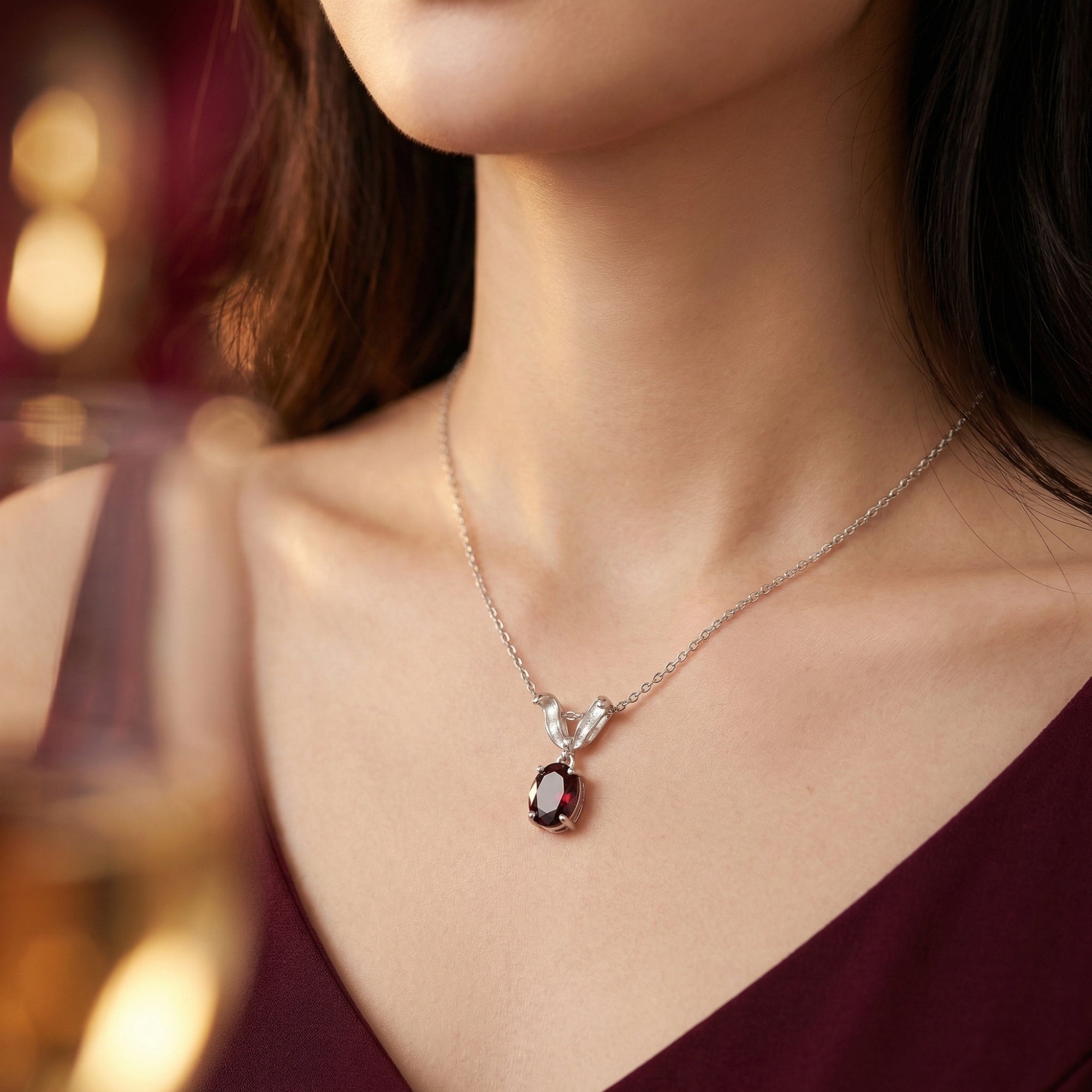 Close-up view of the silver oval garnet pendant necklace resting on a woman's collarbone.