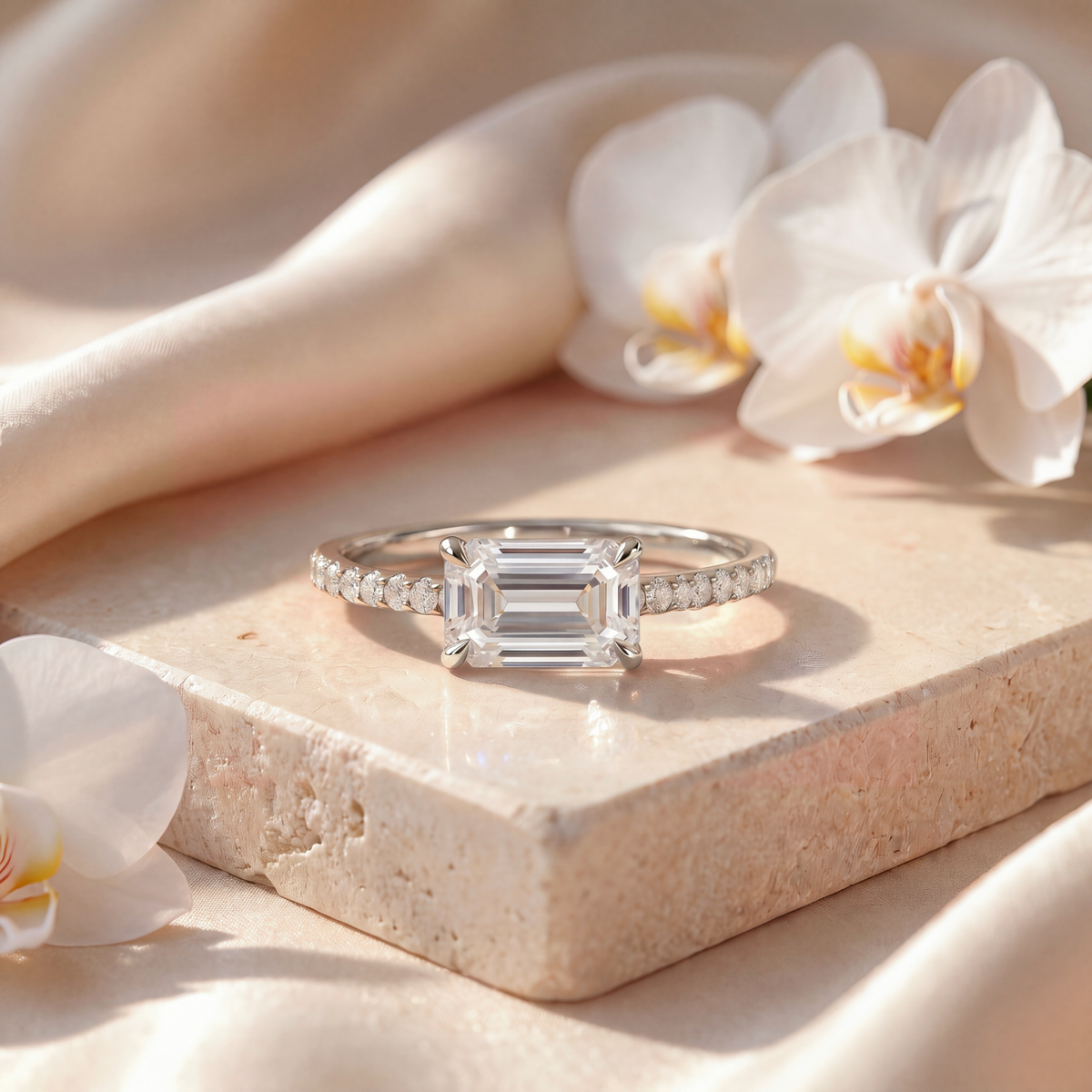 White gold engagement ring featuring an east-west emerald-cut moissanite center stone.