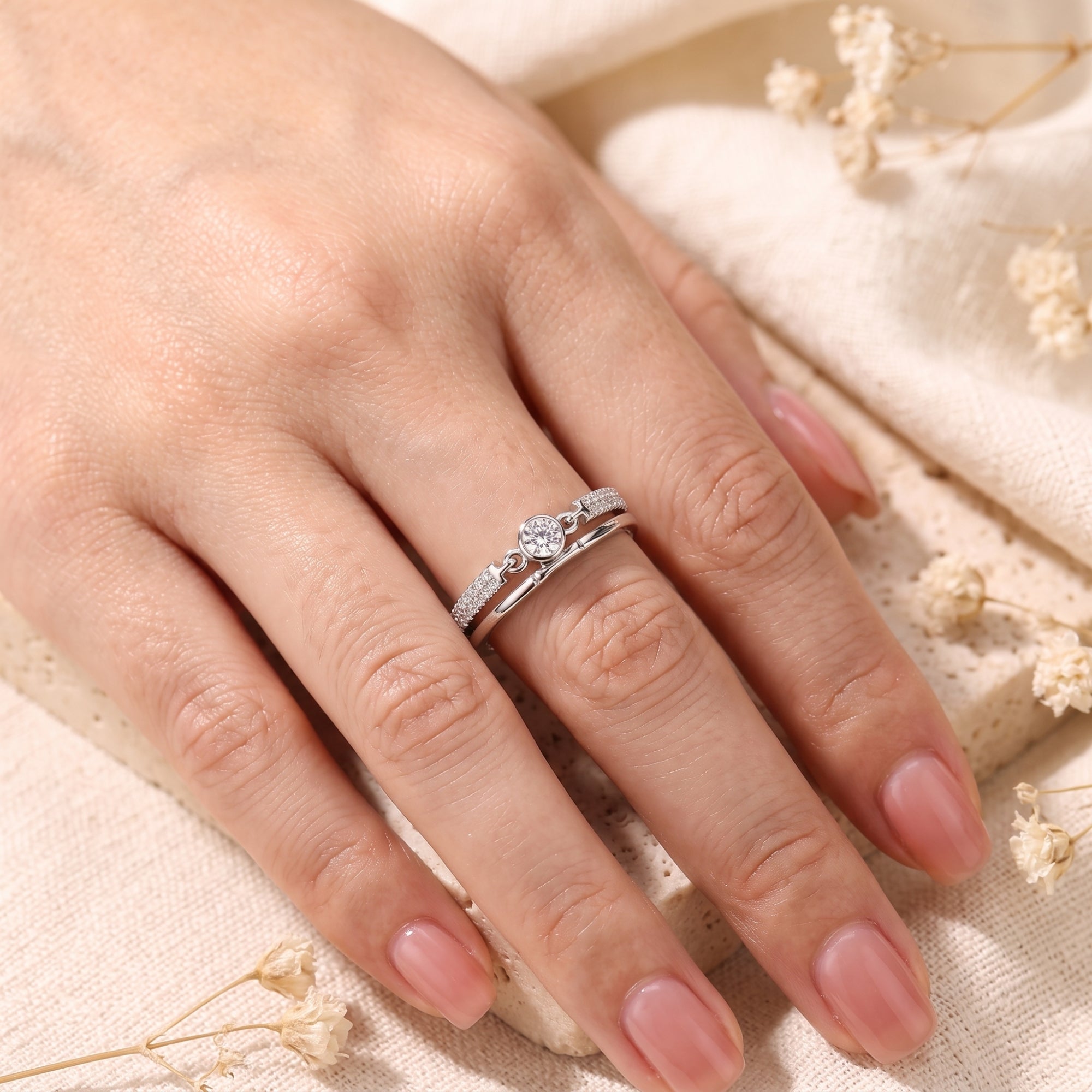 Angled view of the Lyra sterling silver double band ring with round cubic zirconia on a finger.