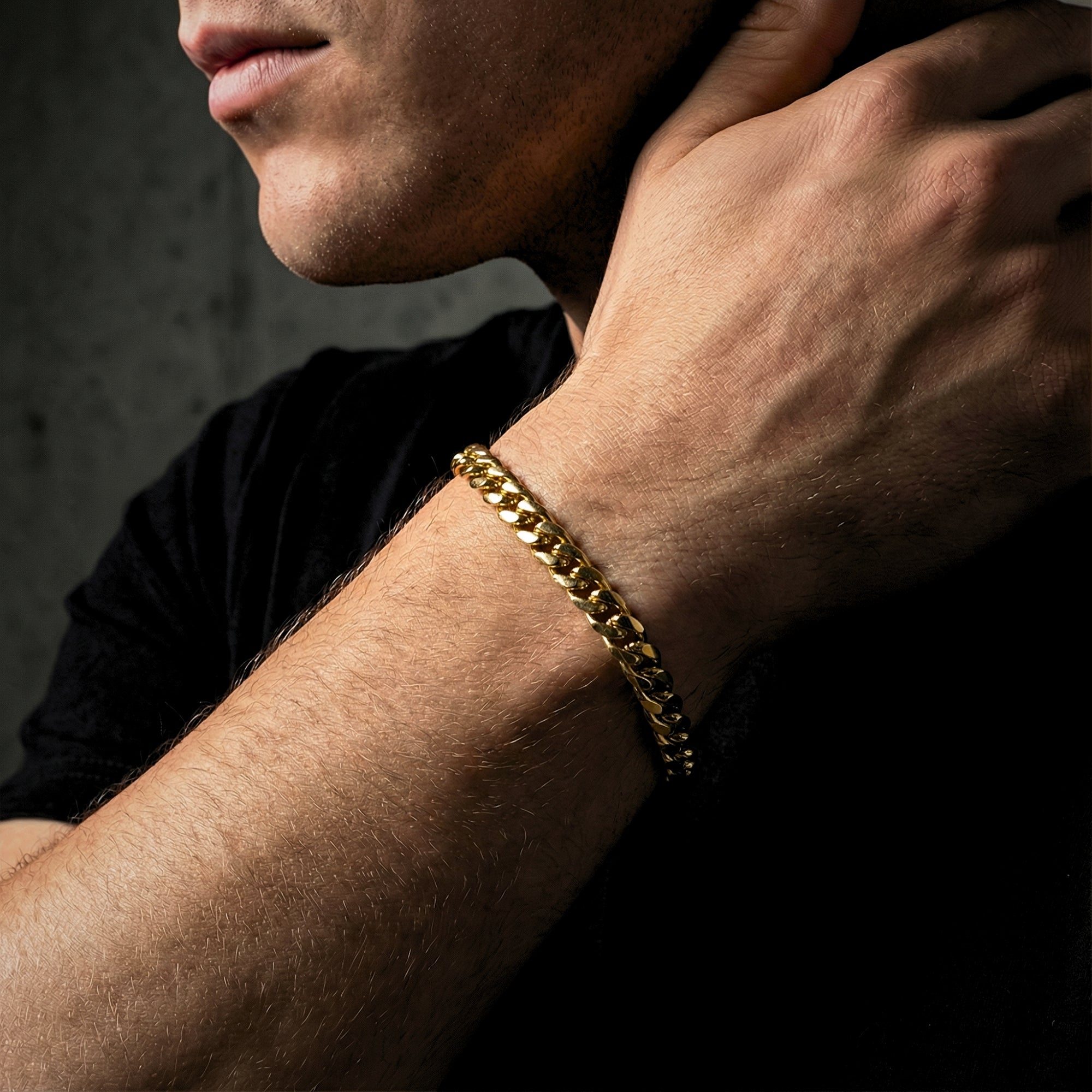 Close-up of a gold stainless steel Cuban link bracelet on a man's wrist.