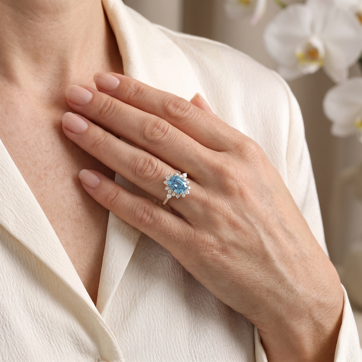 Close-up lifestyle view of the yellow gold blue gemstone ring rested on a model's chest.