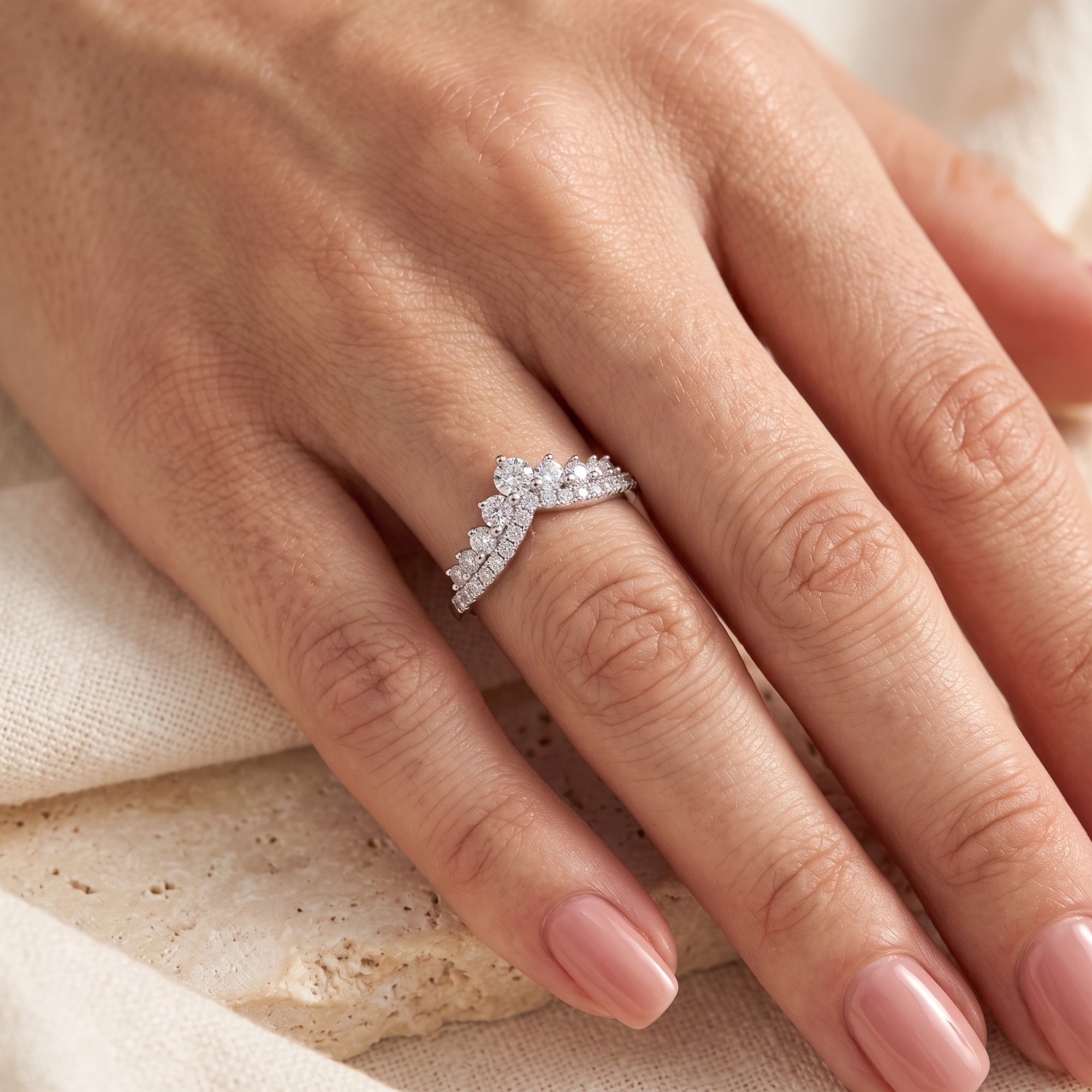 Silver double-row chevron promise ring with brilliant cubic zirconia stones shown on a finger.