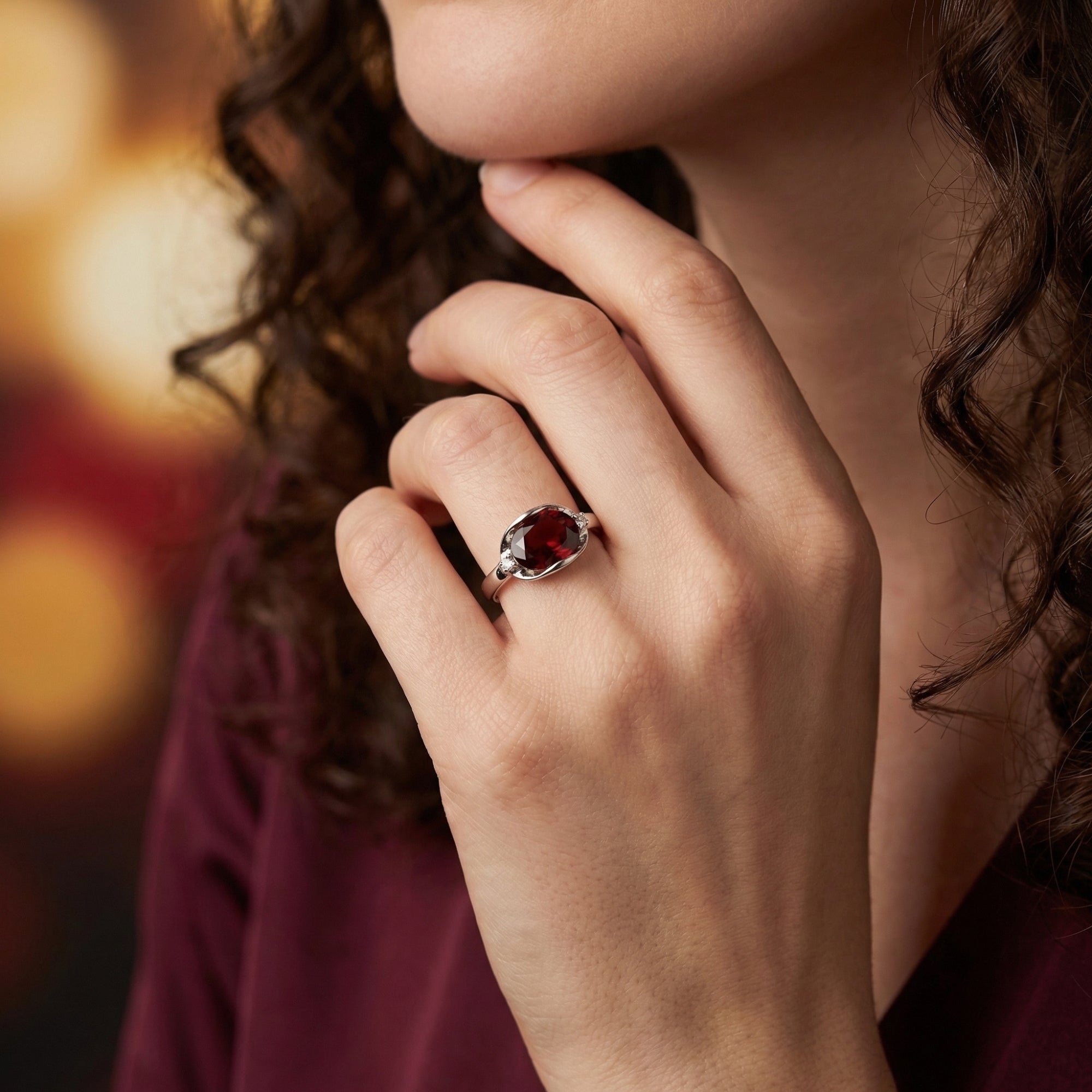 Sterling silver statement ring with a deep red oval garnet worn on a woman's hand.