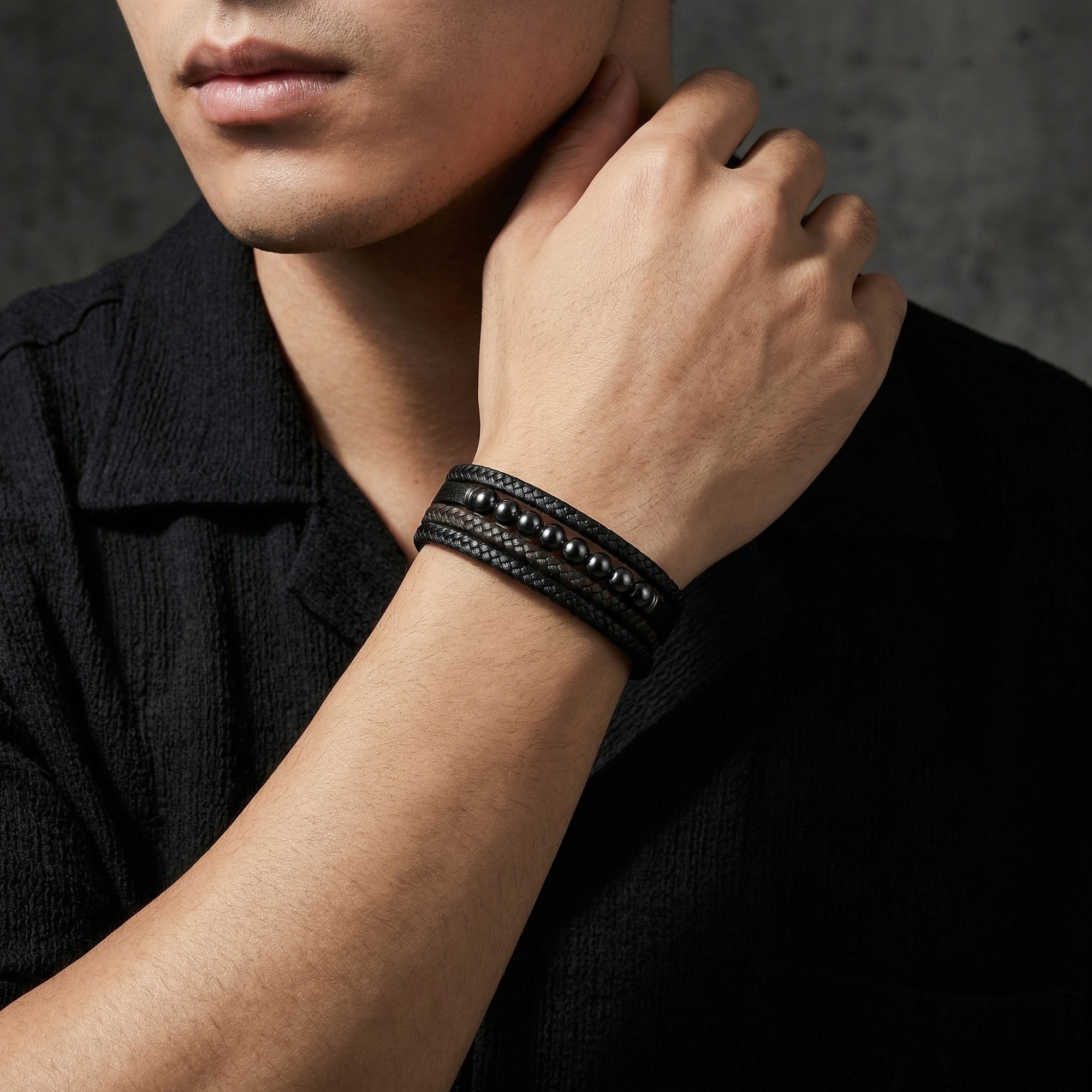 Men's black and brown braided leather bracelet with gunmetal beads shown on a model's wrist.