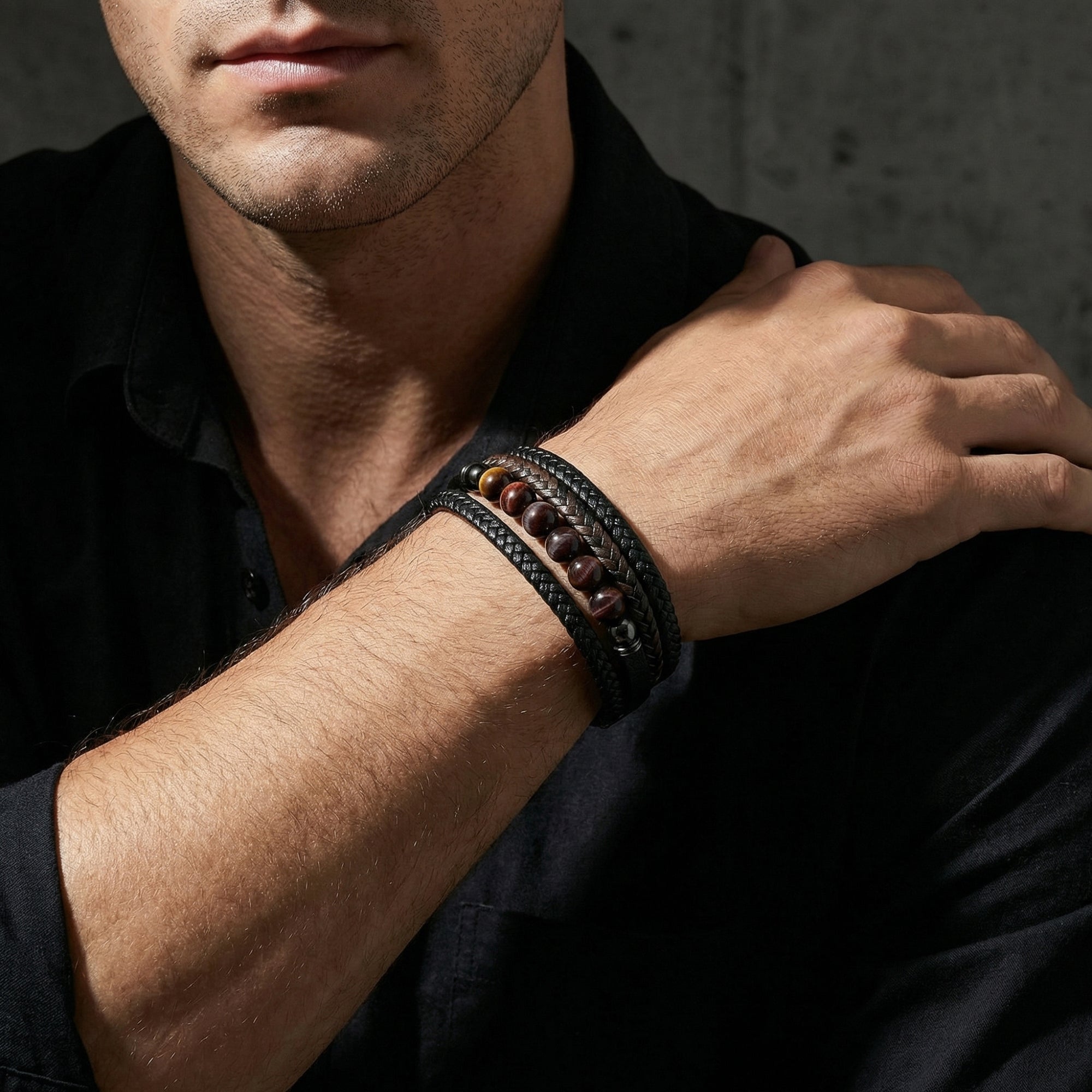 Men's multi-strand black leather bracelet with red tiger's eye beads shown on a model's wrist.