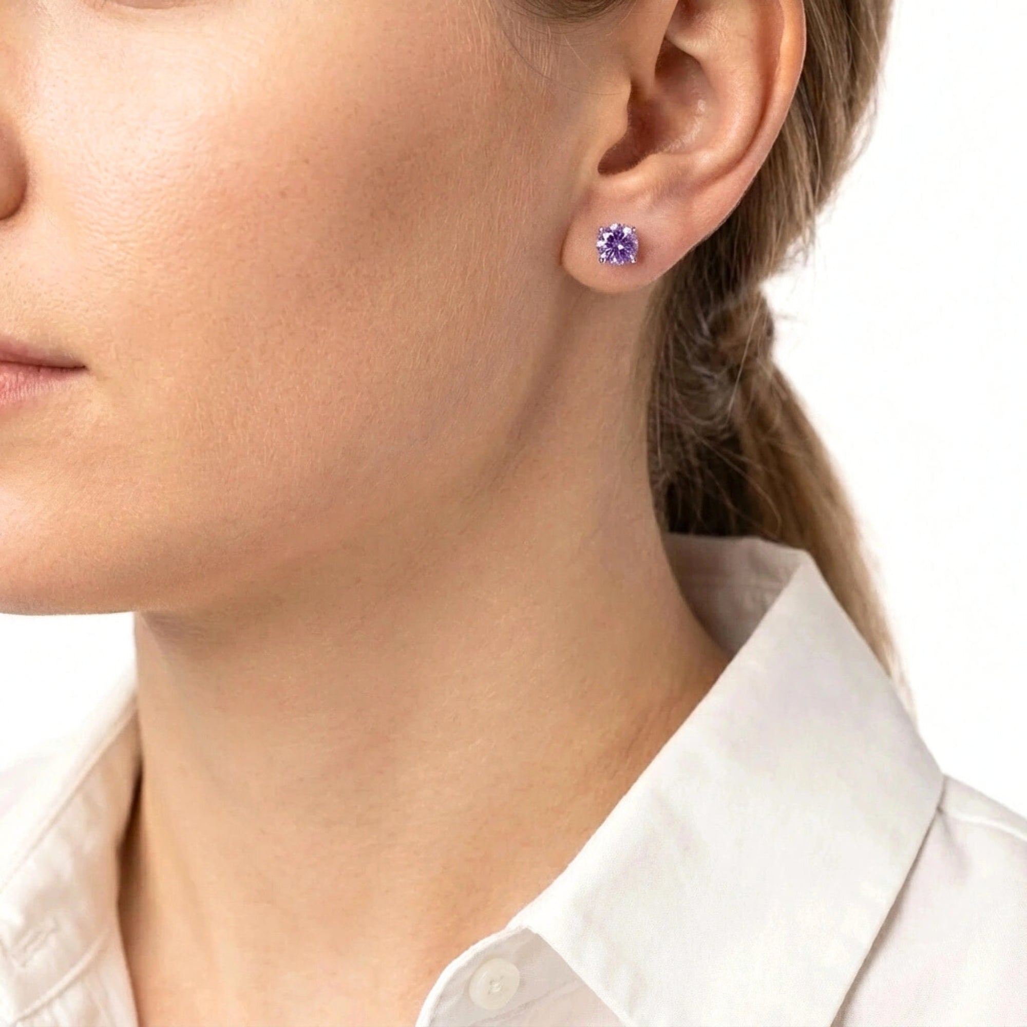 Woman wearing the round cut simulated amethyst sterling silver stud earrings for a classic everyday look.