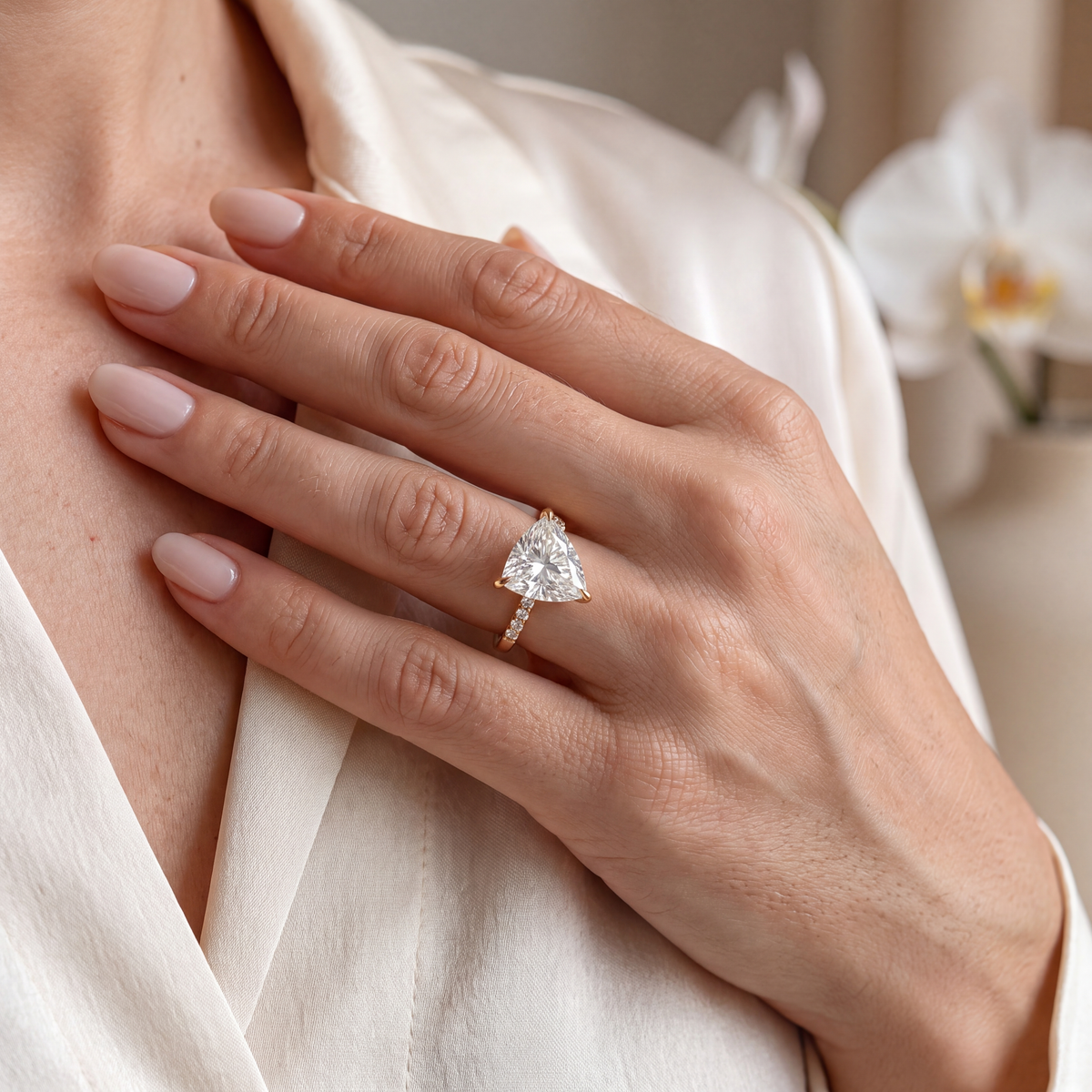 Yellow gold trillion-cut moissanite engagement ring showcased on a model's hand.