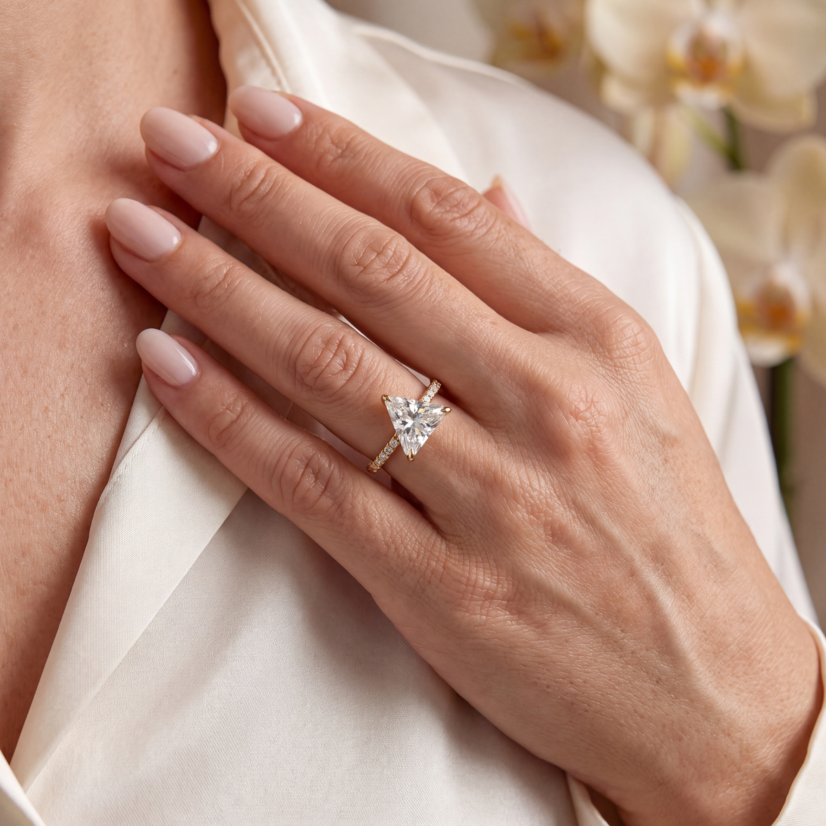 Lifestyle view of the yellow gold triangle-cut moissanite ring worn on a woman's hand.