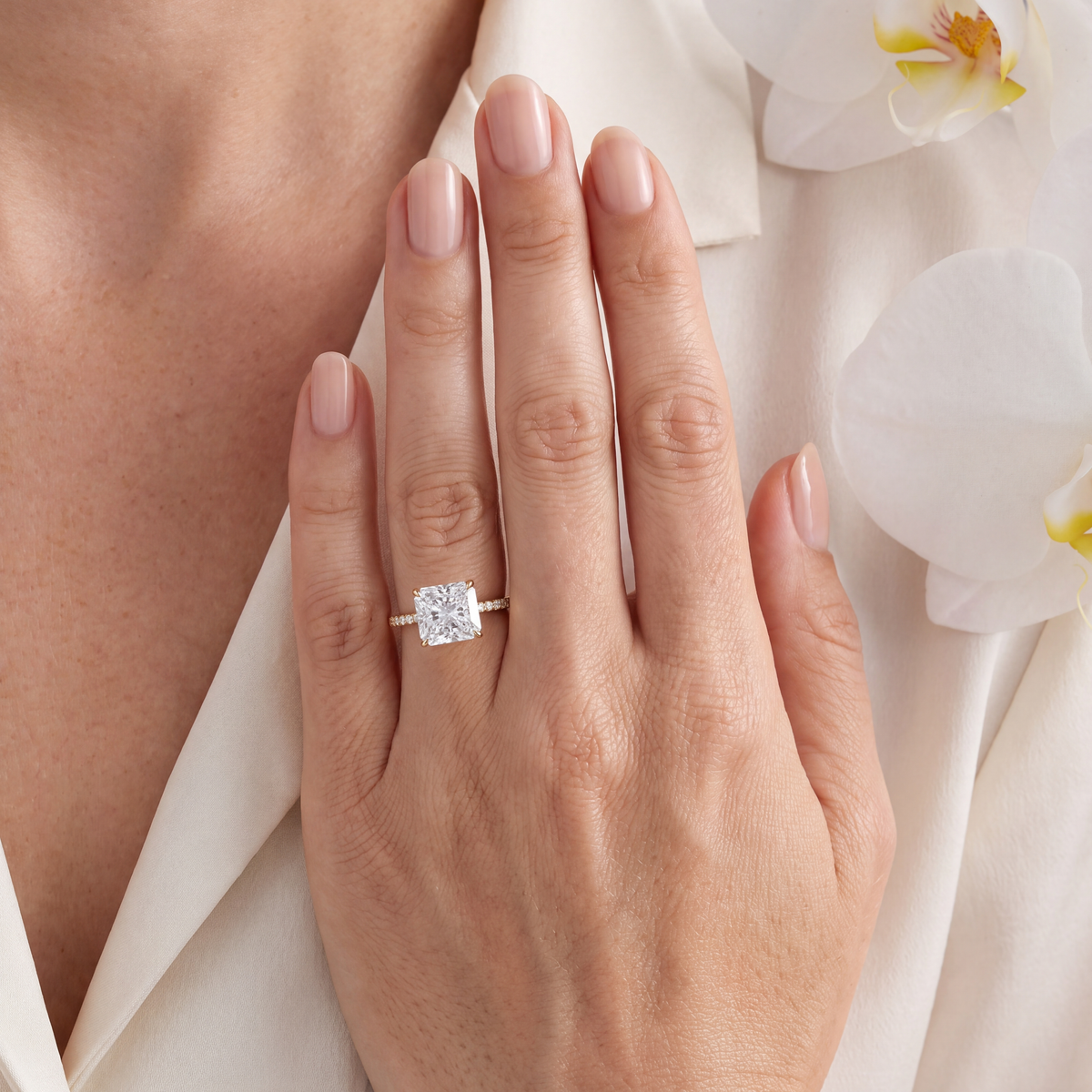 Model wearing a yellow gold radiant cut moissanite engagement ring with a pavé diamond band.