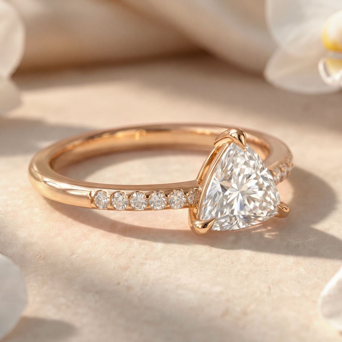 Angled side profile of a yellow gold trillion-cut moissanite engagement ring on a stone surface.